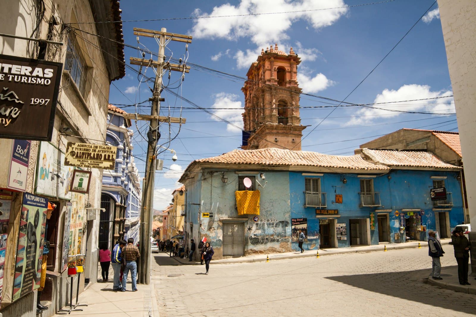 Potosí — a group of people walking down a street next to tall buildings