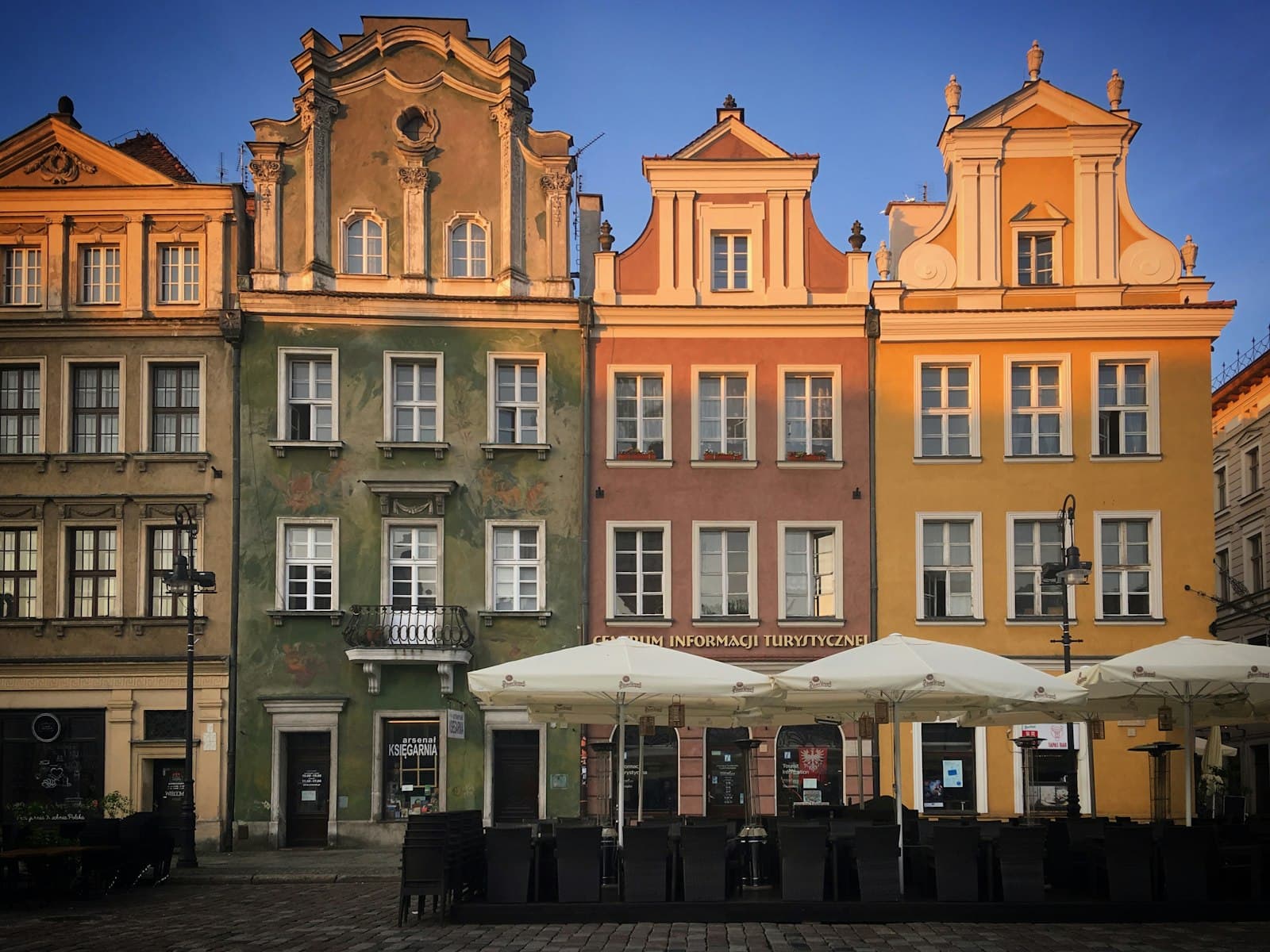 Poznań — a row of buildings with tables and umbrellas in front of them