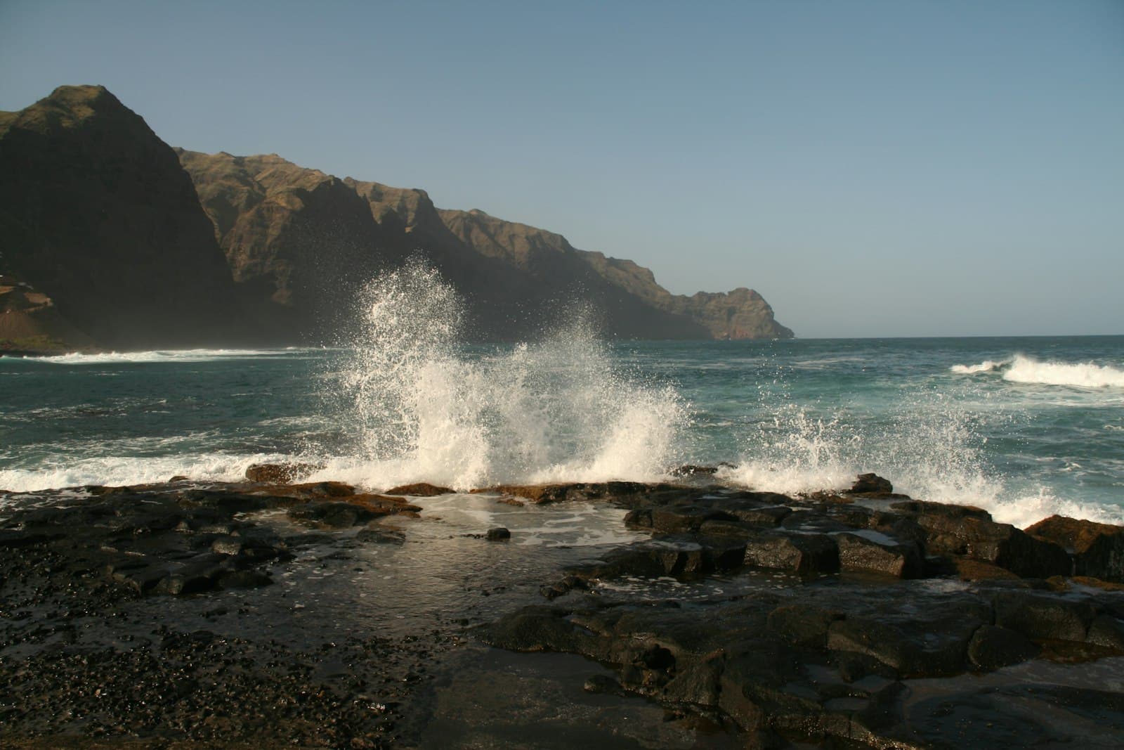 Praia — a large wave hitting the rocks on the beach
