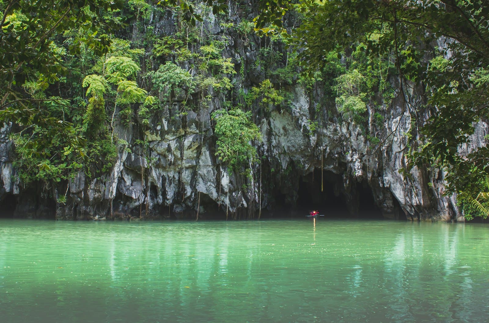 Puerto Princesa — person in red shirt standing on rock in the middle of lake during daytime