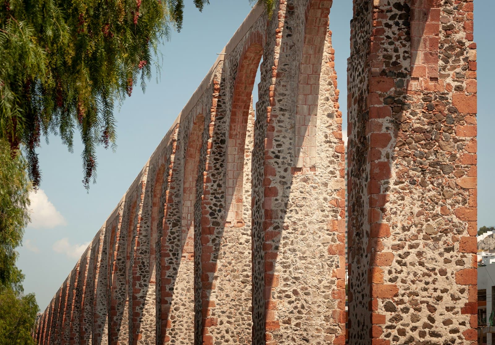 Querétaro — a row of stone pillars next to a tree