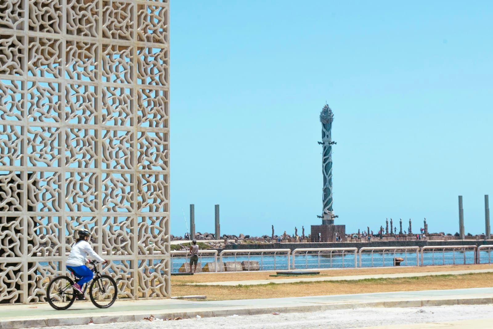 Recife — a person riding a bicycle on a road next to a large metal structure