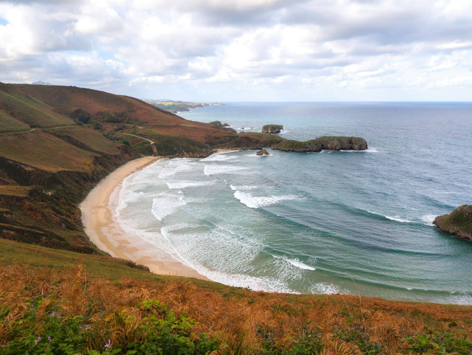 Ribadesella — A view of a beach from a hill overlooking the ocean