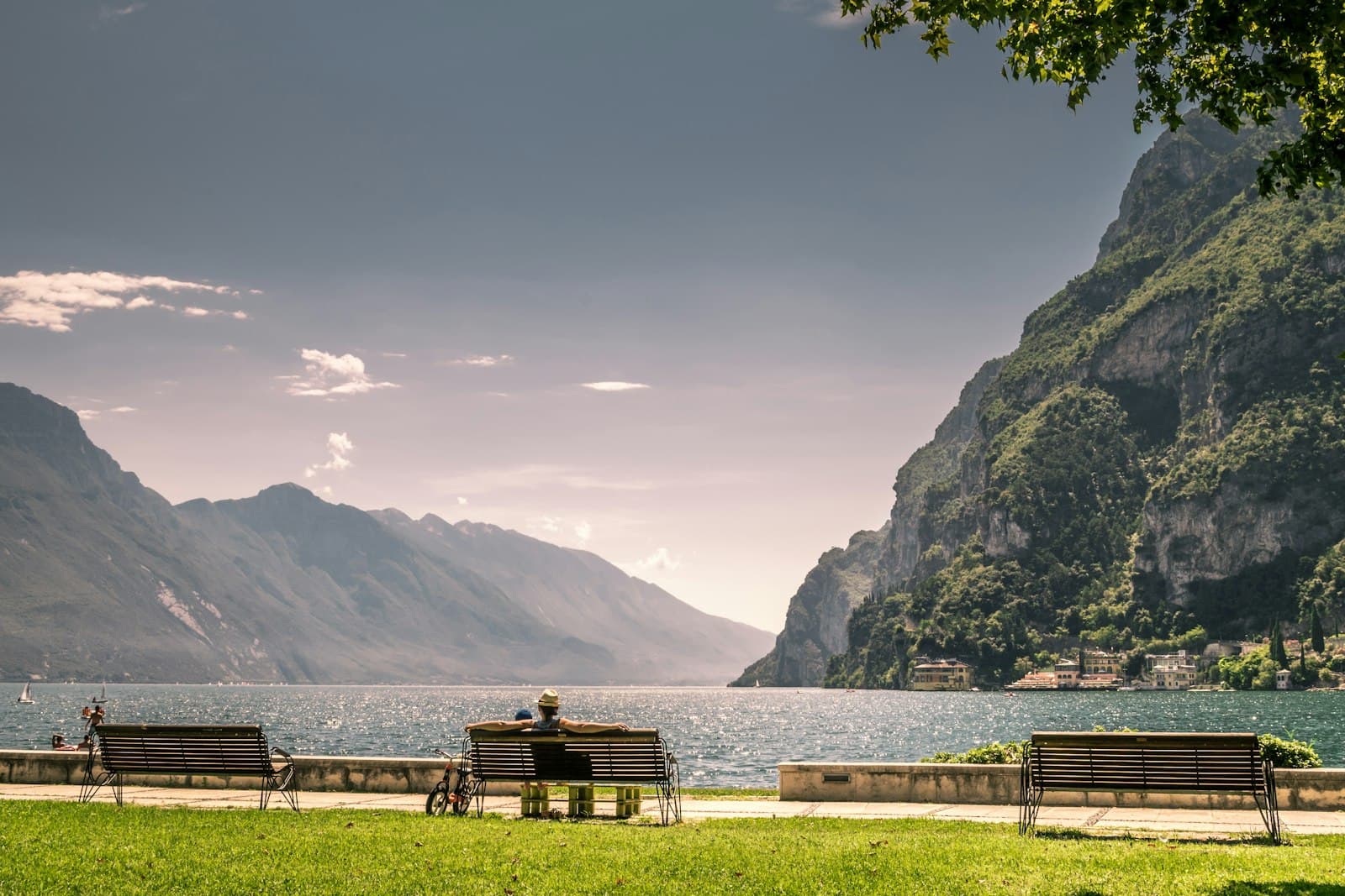 Riva del Garda — brown wooden bench on green grass field near body of water during daytime