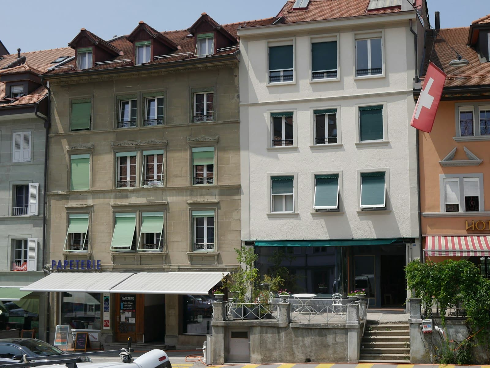 Romont — Historic european buildings with green shutters and a swiss flag.