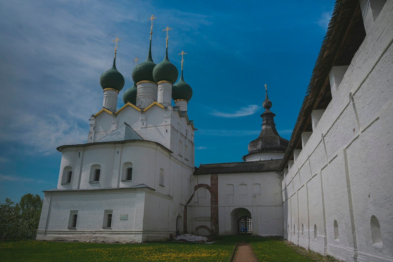 Rostov Veliki — White church with green domes under blue sky.