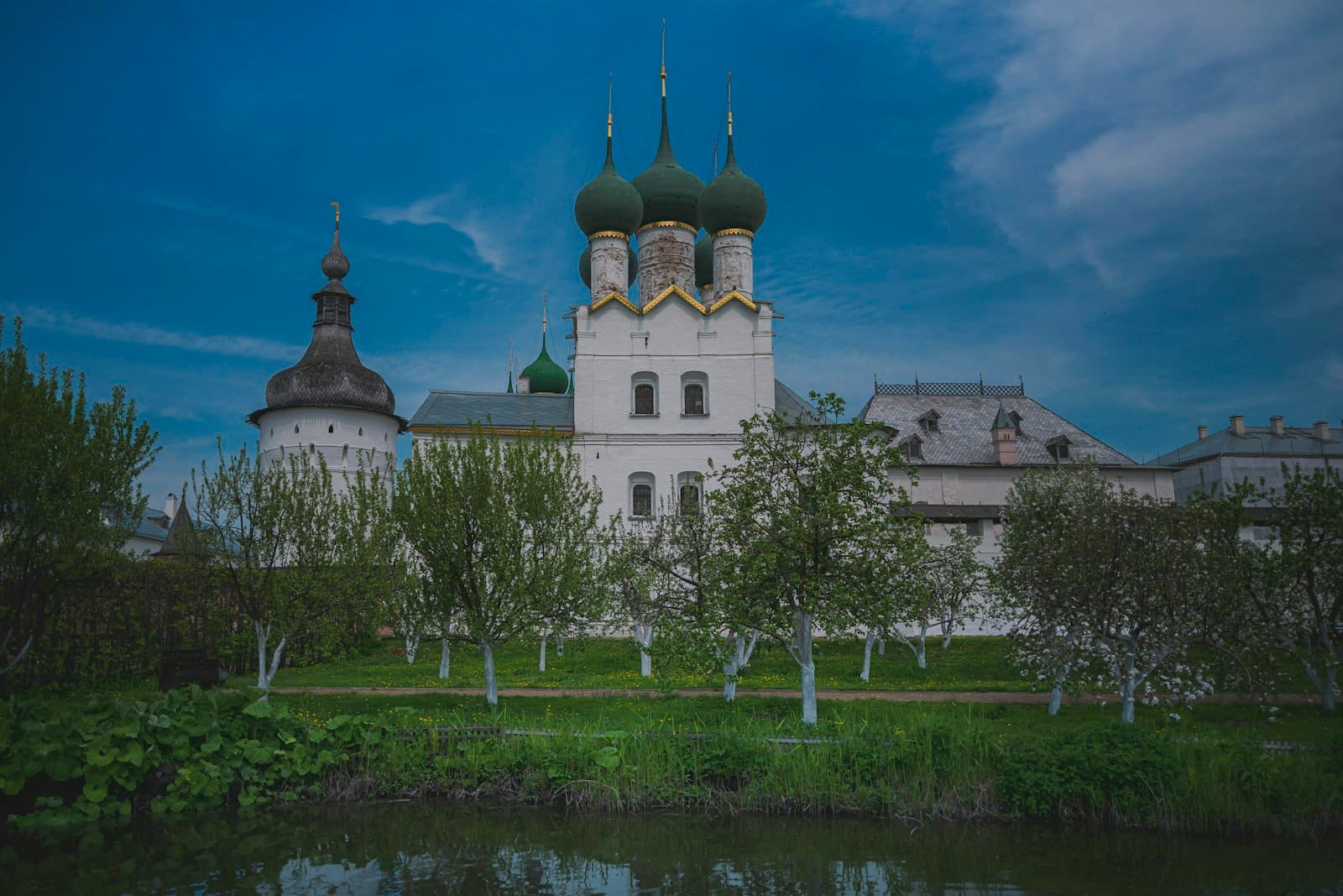 Rostov Veliki — White church with green domes under blue sky.