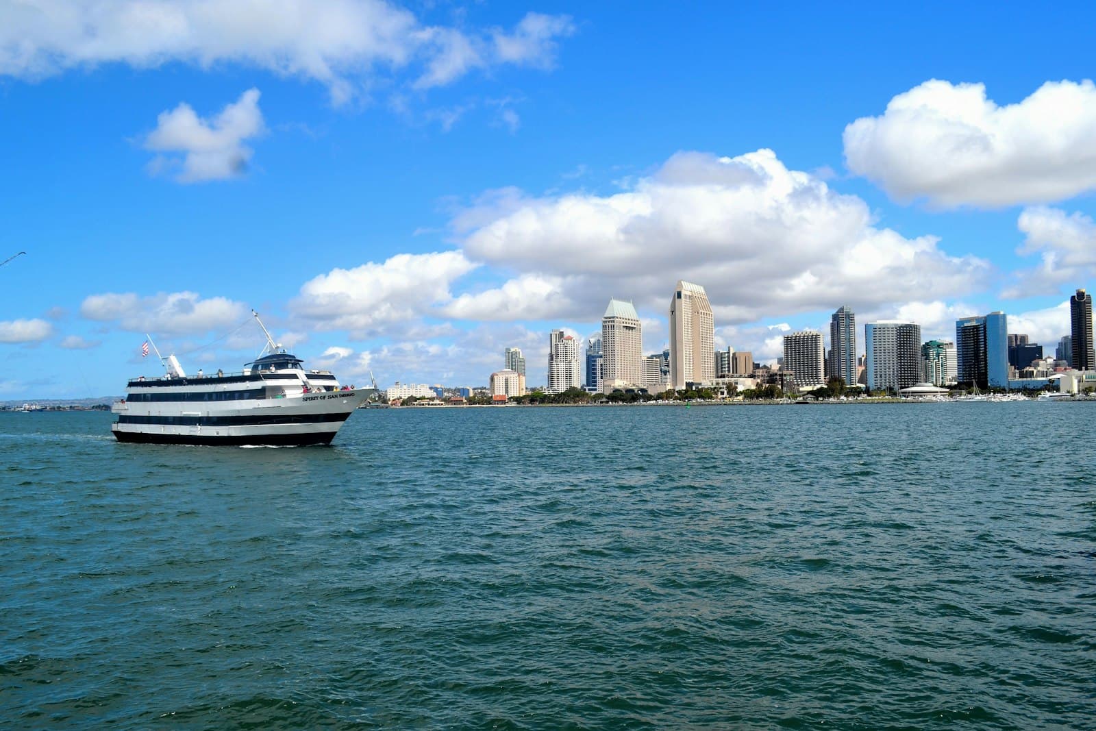 San Diego — white and black boat on sea near city buildings under blue and white sunny cloudy sky