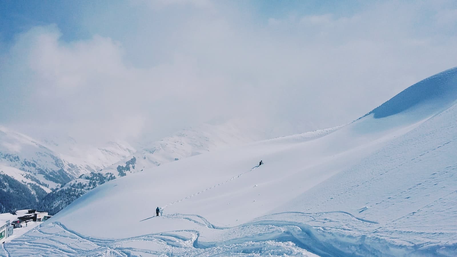 Sankt Anton am Arlberg — two people hiking on snow covered hill during day