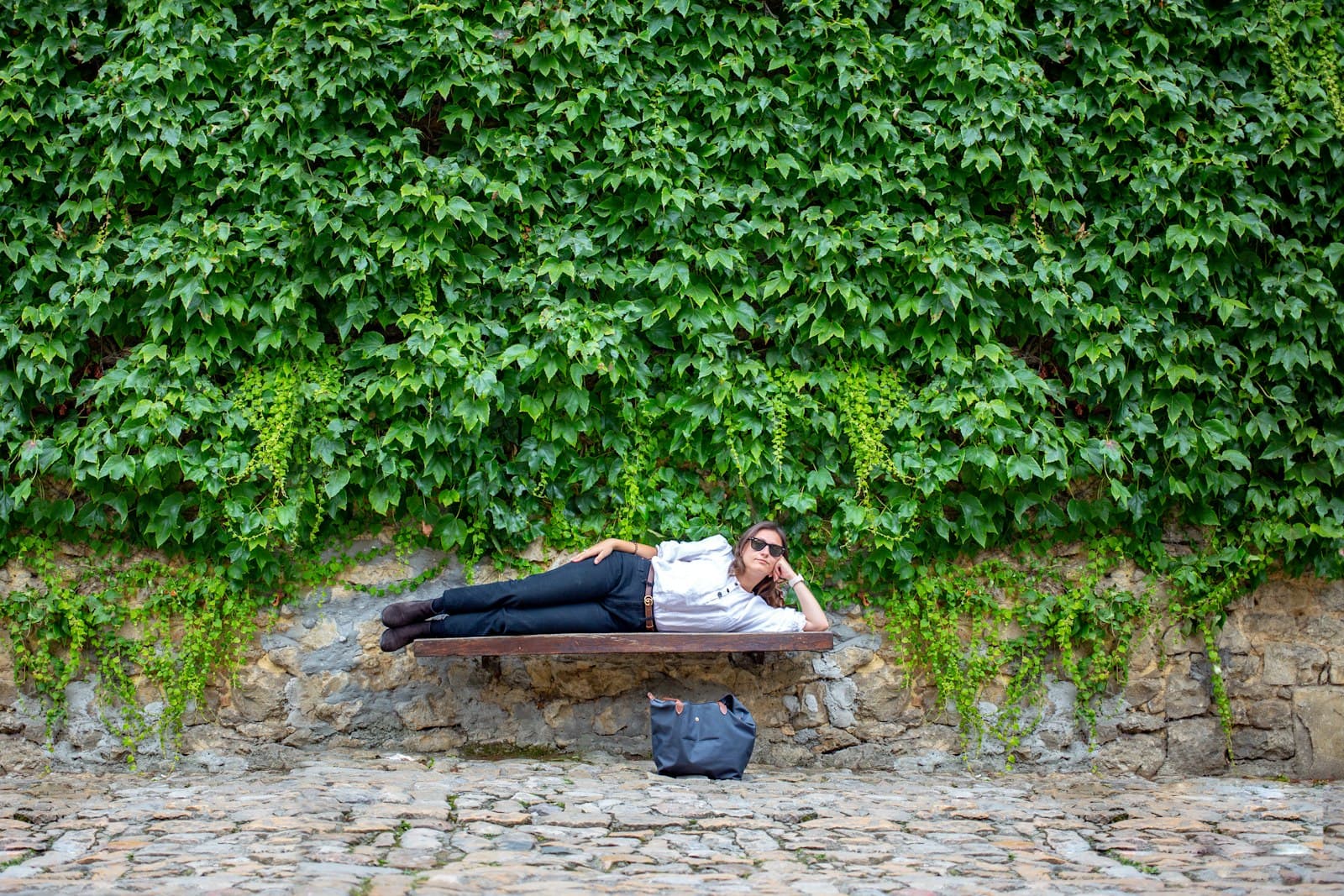 Santillana del Mar — woman lying on brown wooden bench