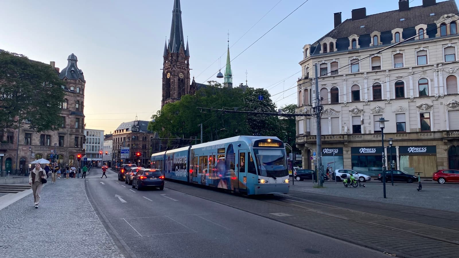 Saarbrücken — a blue and white train traveling down a street next to tall buildings