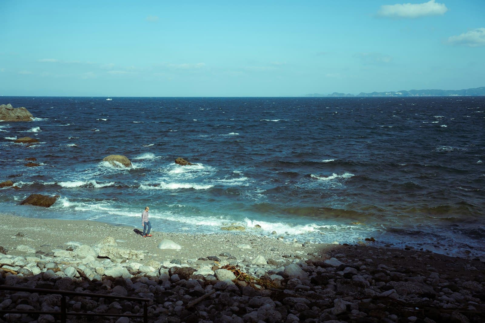 Shimoda — Waves crash on a rocky beach under a clear sky.