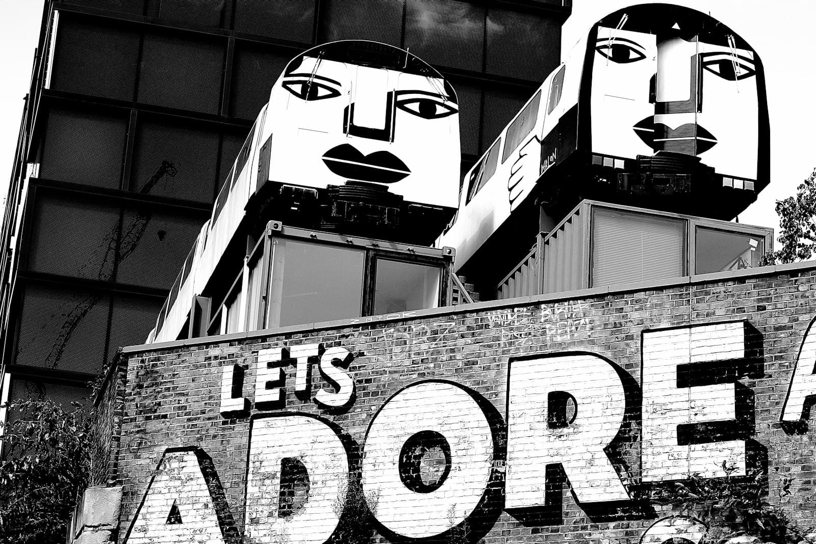Shoreditch Street Art — a black and white photo of a sign that says let's adore