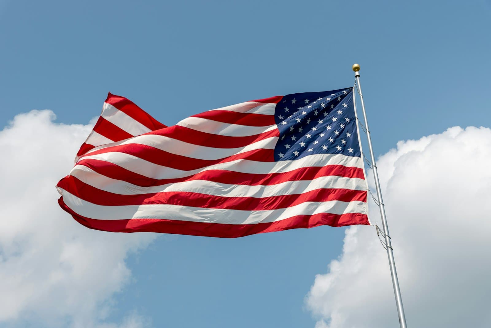 Sioux Falls — An american flag waving against a blue sky with clouds.