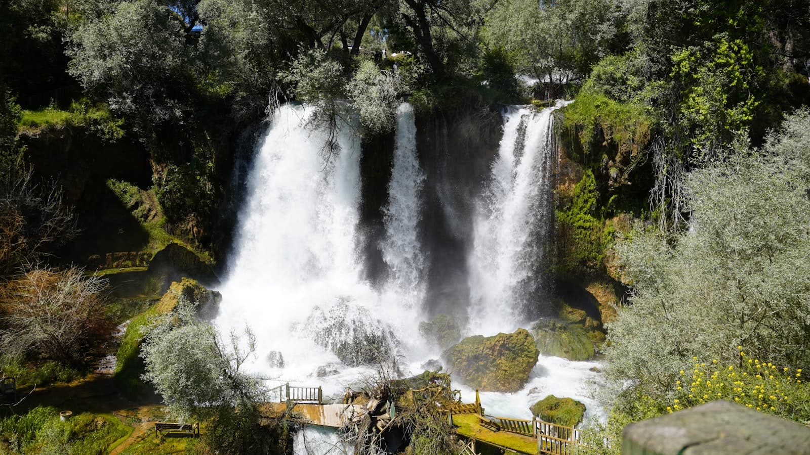 Sivas — Multiple waterfalls cascade down a lush, green rock face.