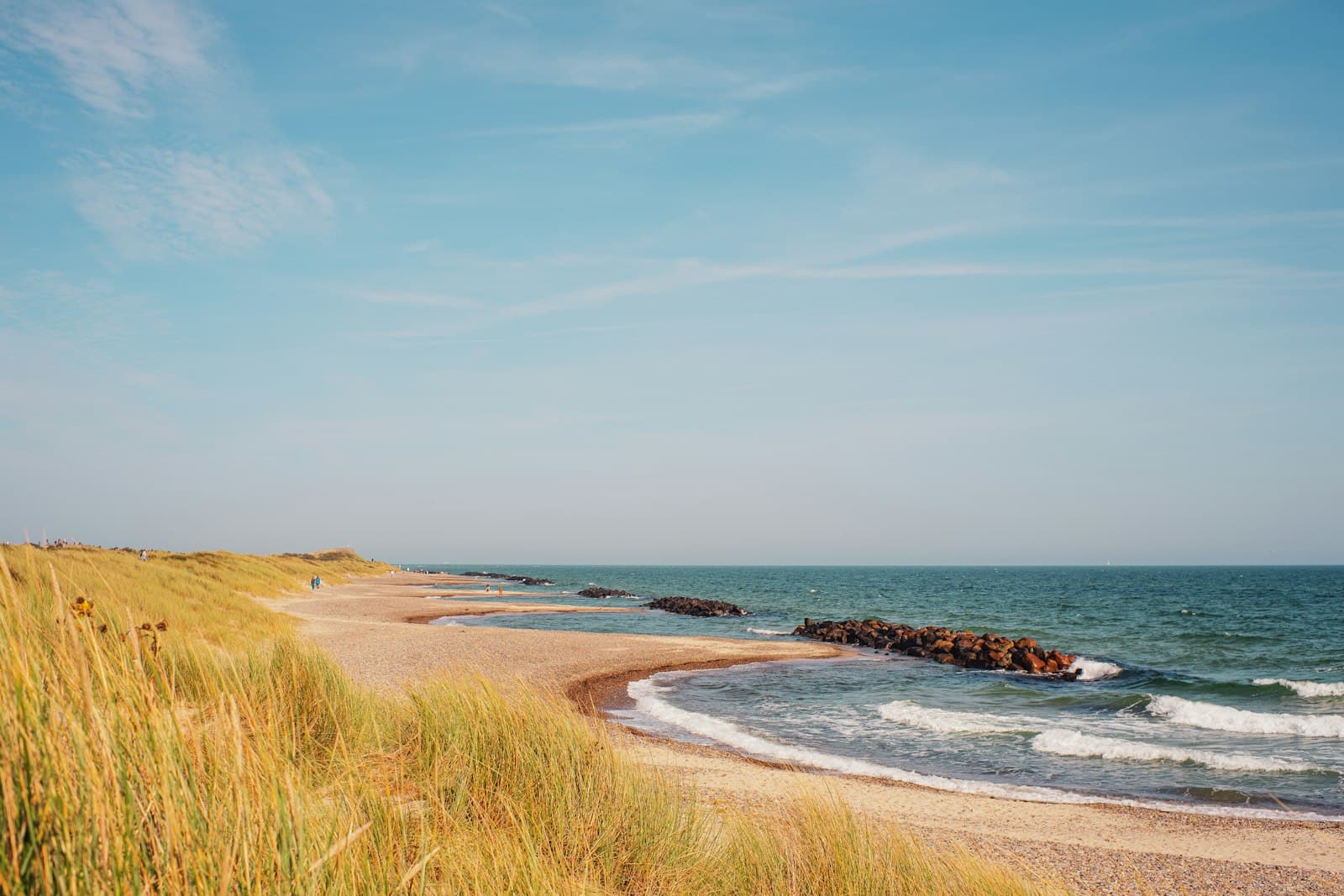 Skagen — A sandy beach next to the ocean under a blue sky