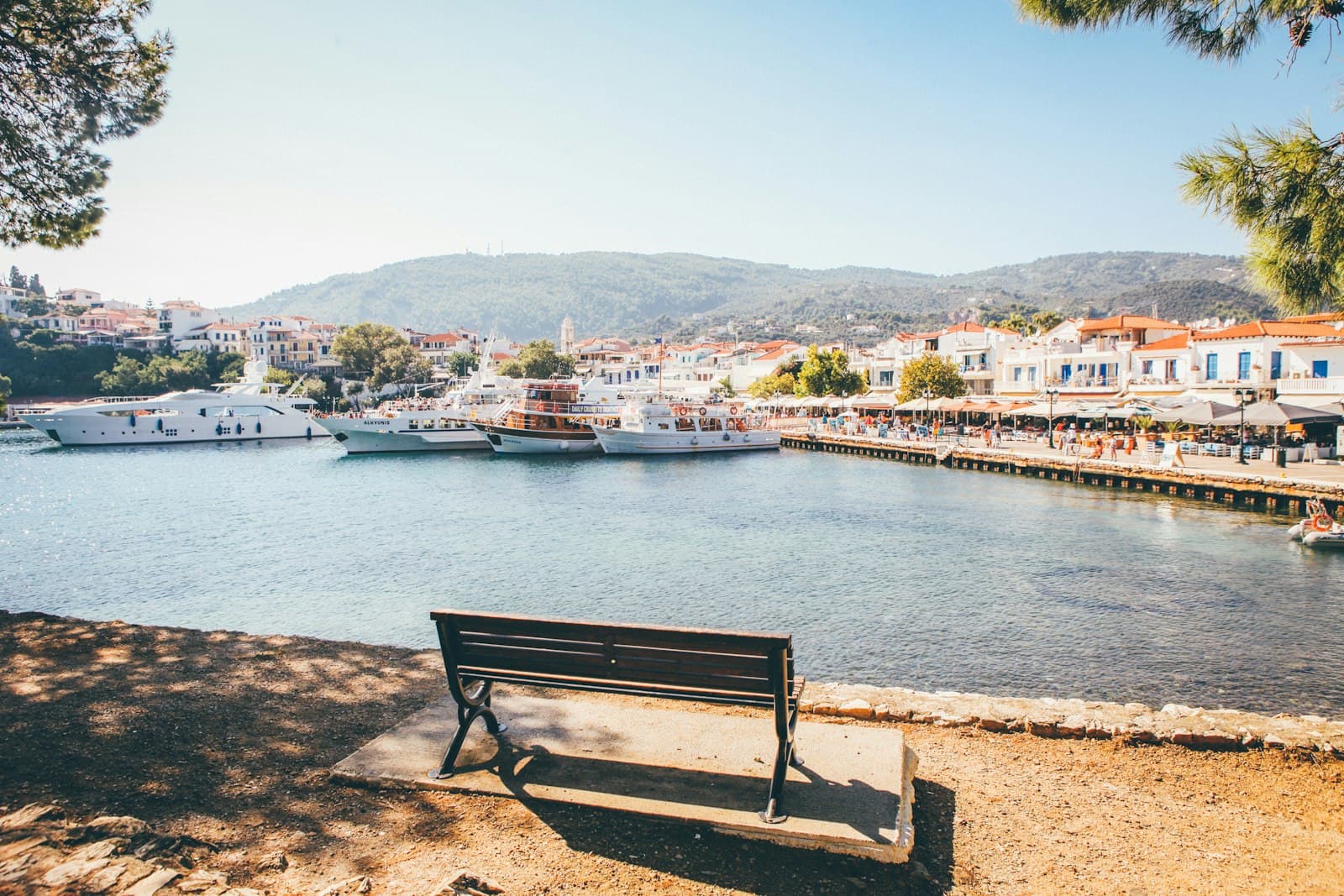 Skiathos — brown wooden bench near body of water during daytime