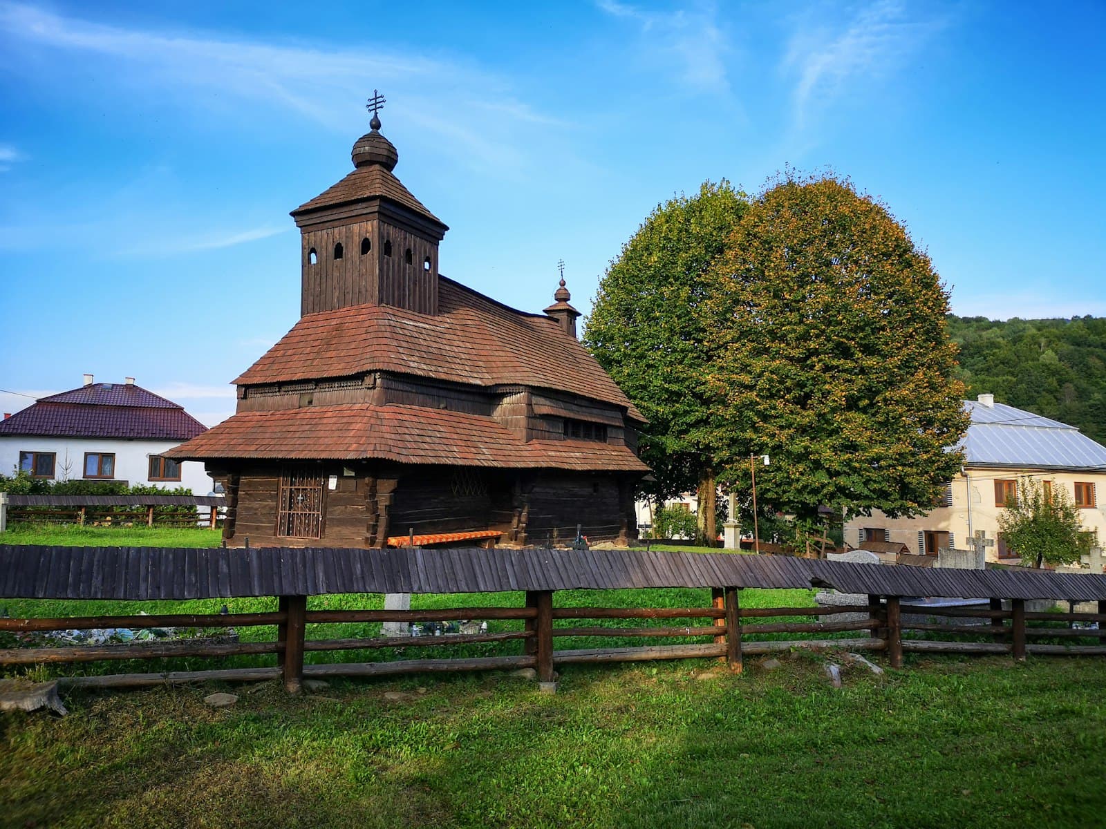 Spišská Sobota — brown wooden fence near green trees under blue sky during daytime