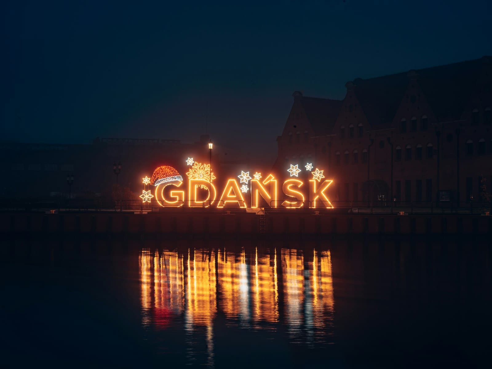 Starogard Gdański — a lighted sign that says gdansk in front of a body of water