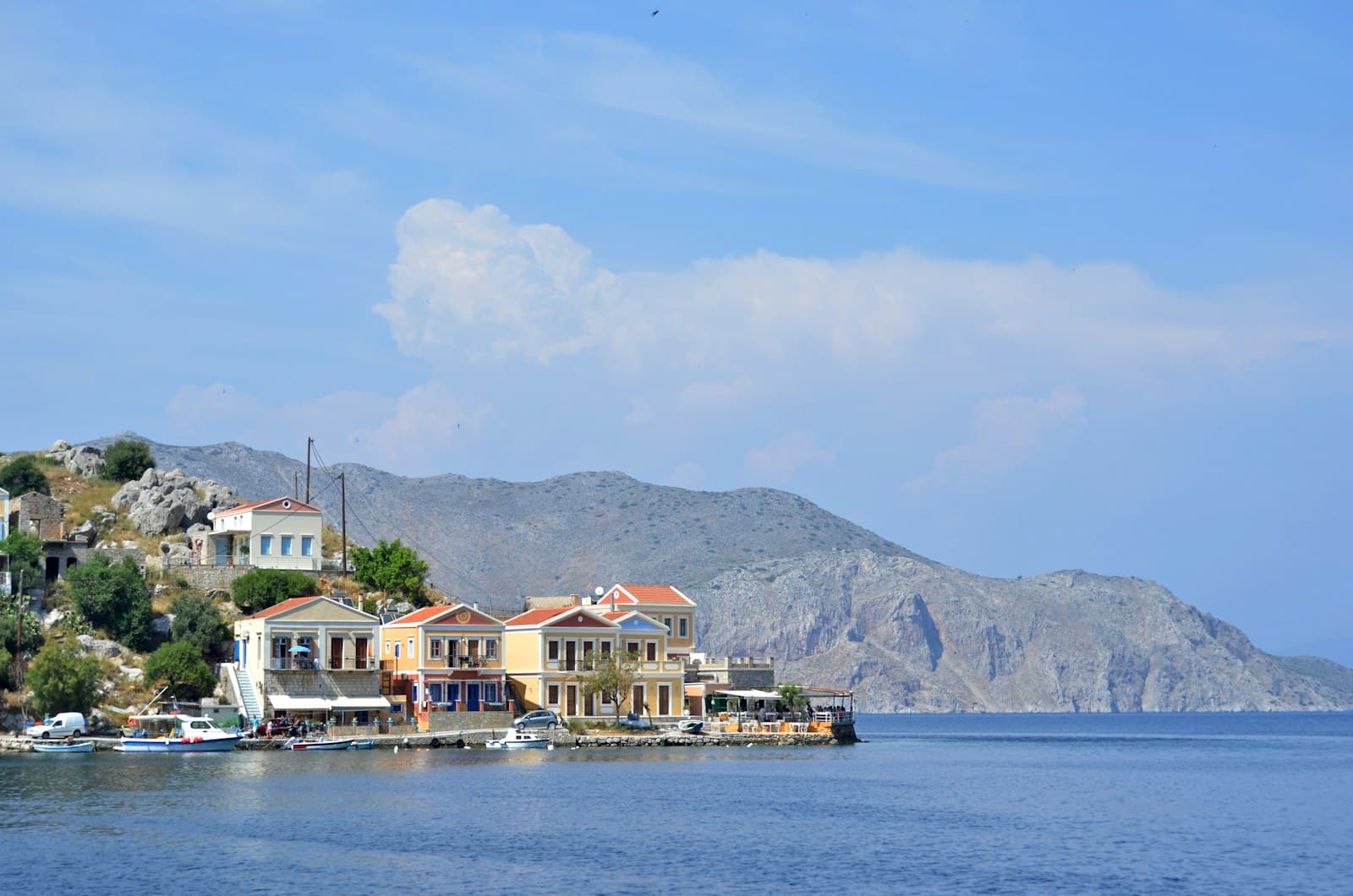 Symi — a row of houses sitting on top of a hill next to a body of water