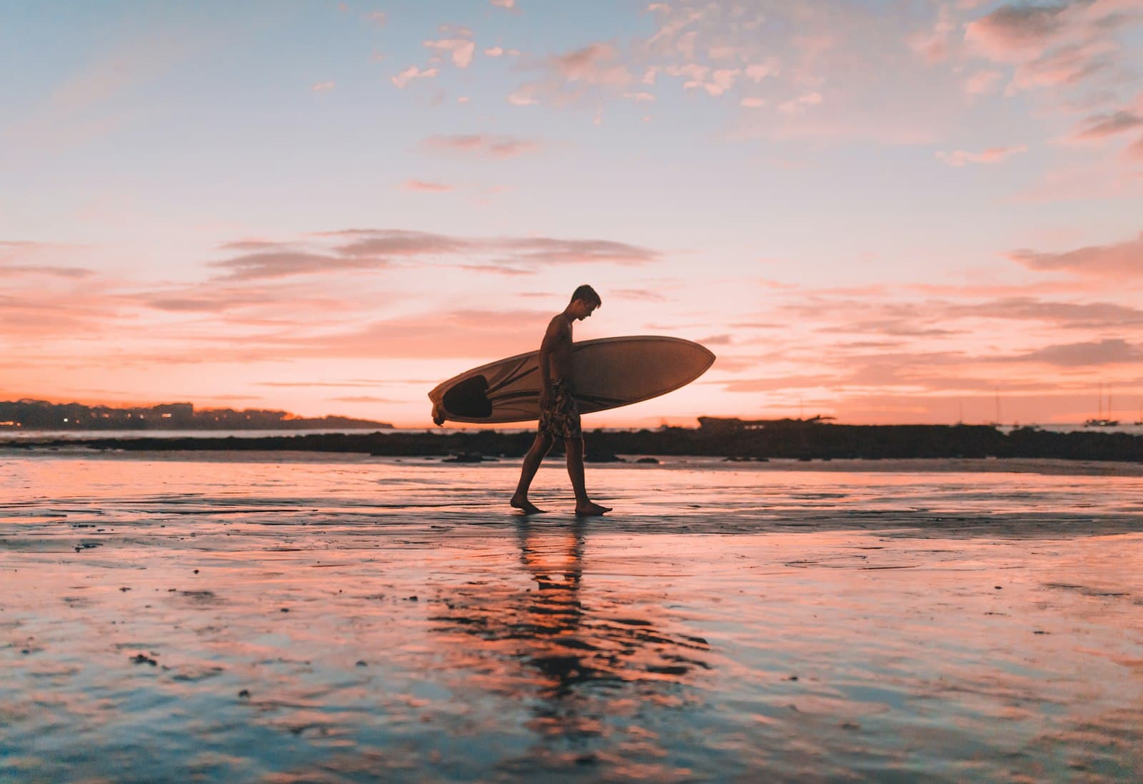 Tamarindo — man holding surfboard walking near seashore