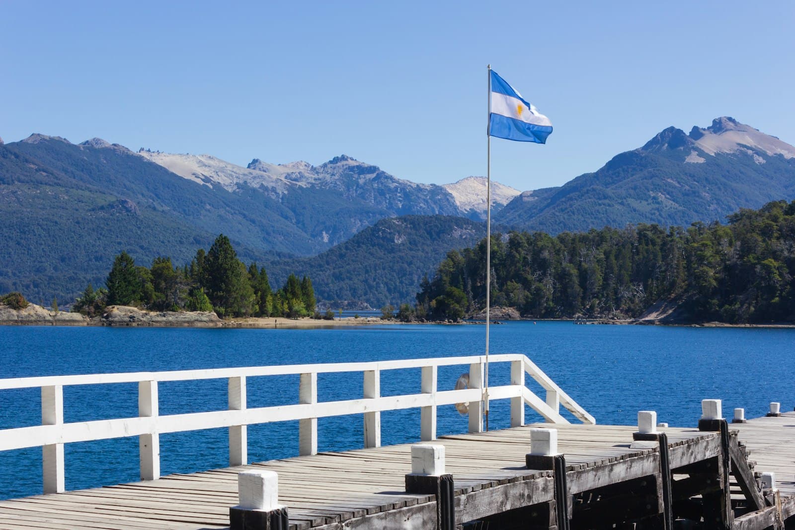 Tandil — white and blue flag on wooden dock near body of water during daytime