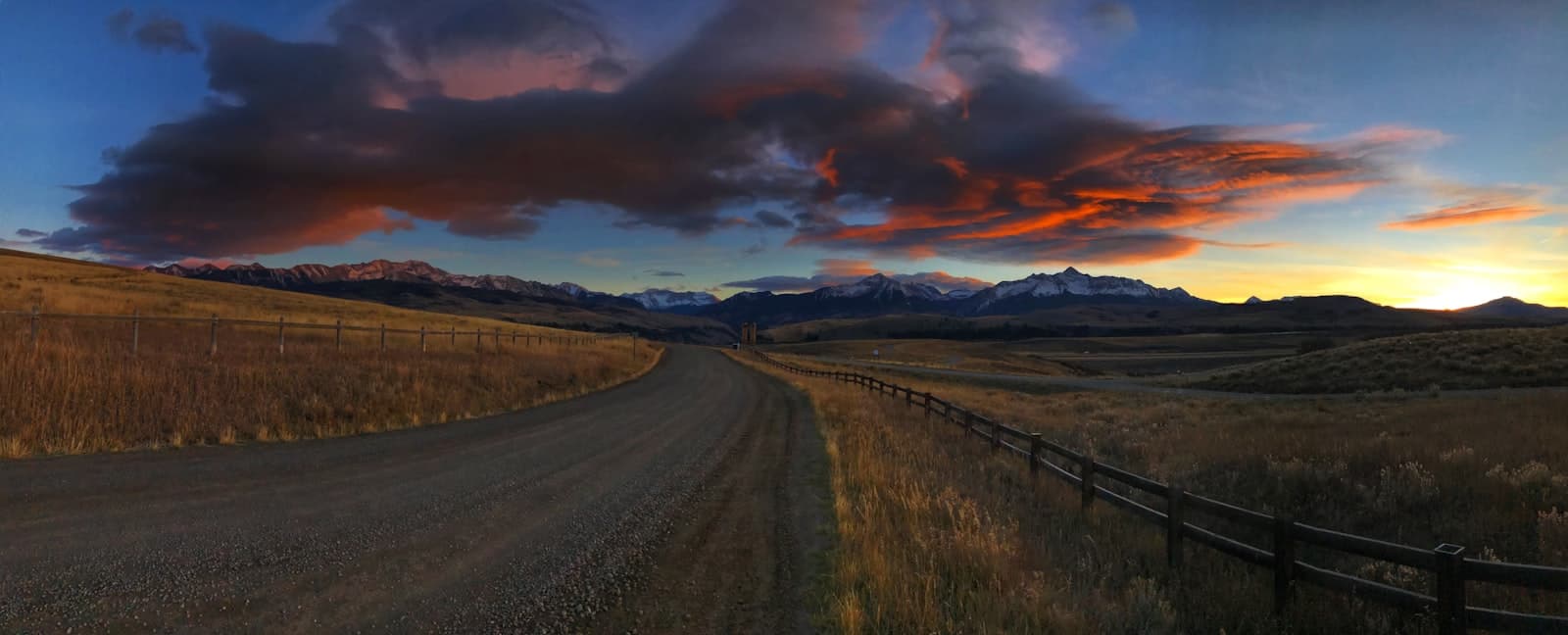 Telluride — gray asphalt road between green grass field under orange and gray cloudy sky
