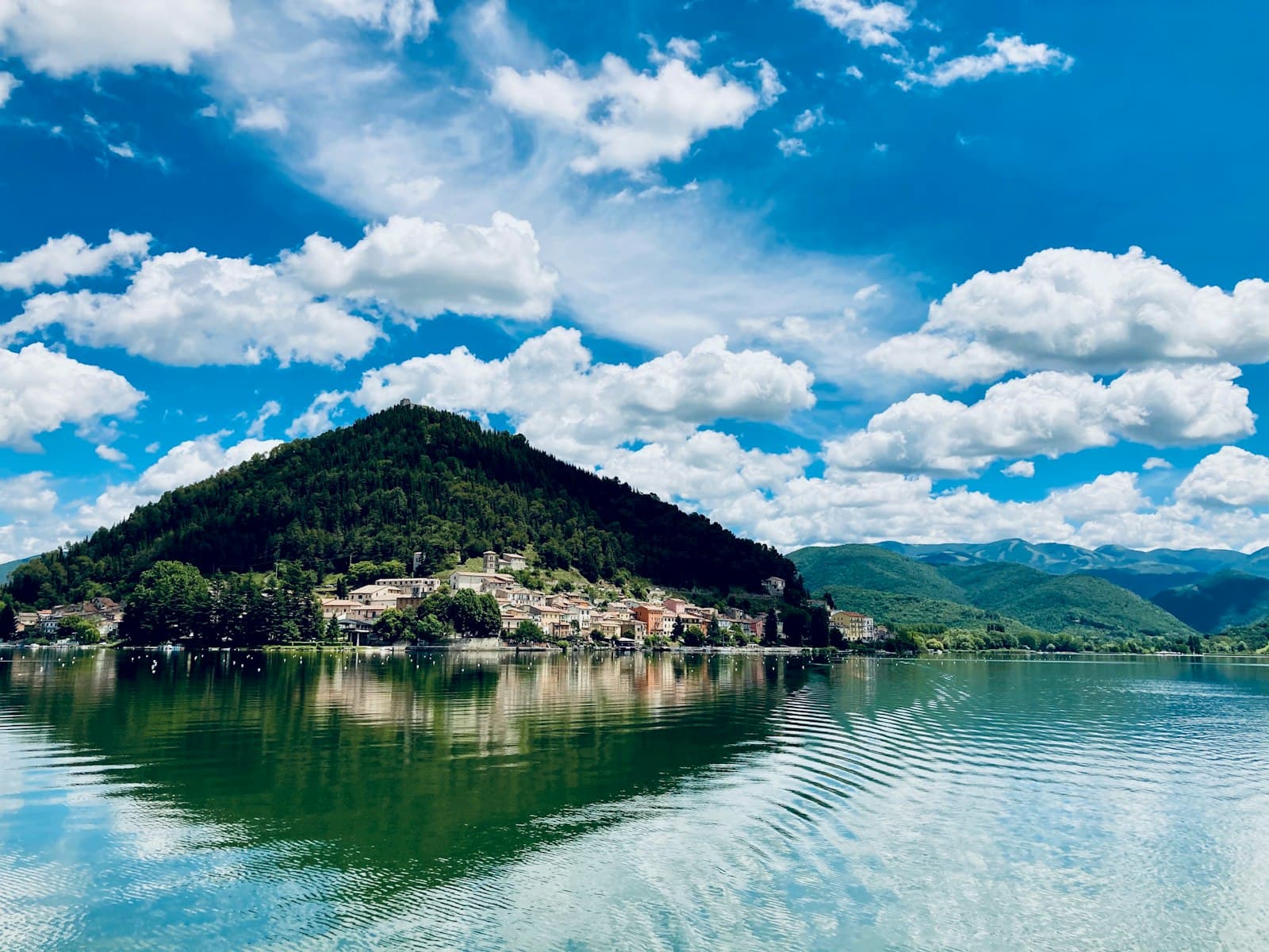 Terni — green trees on island surrounded by water under blue and white cloudy sky during daytime