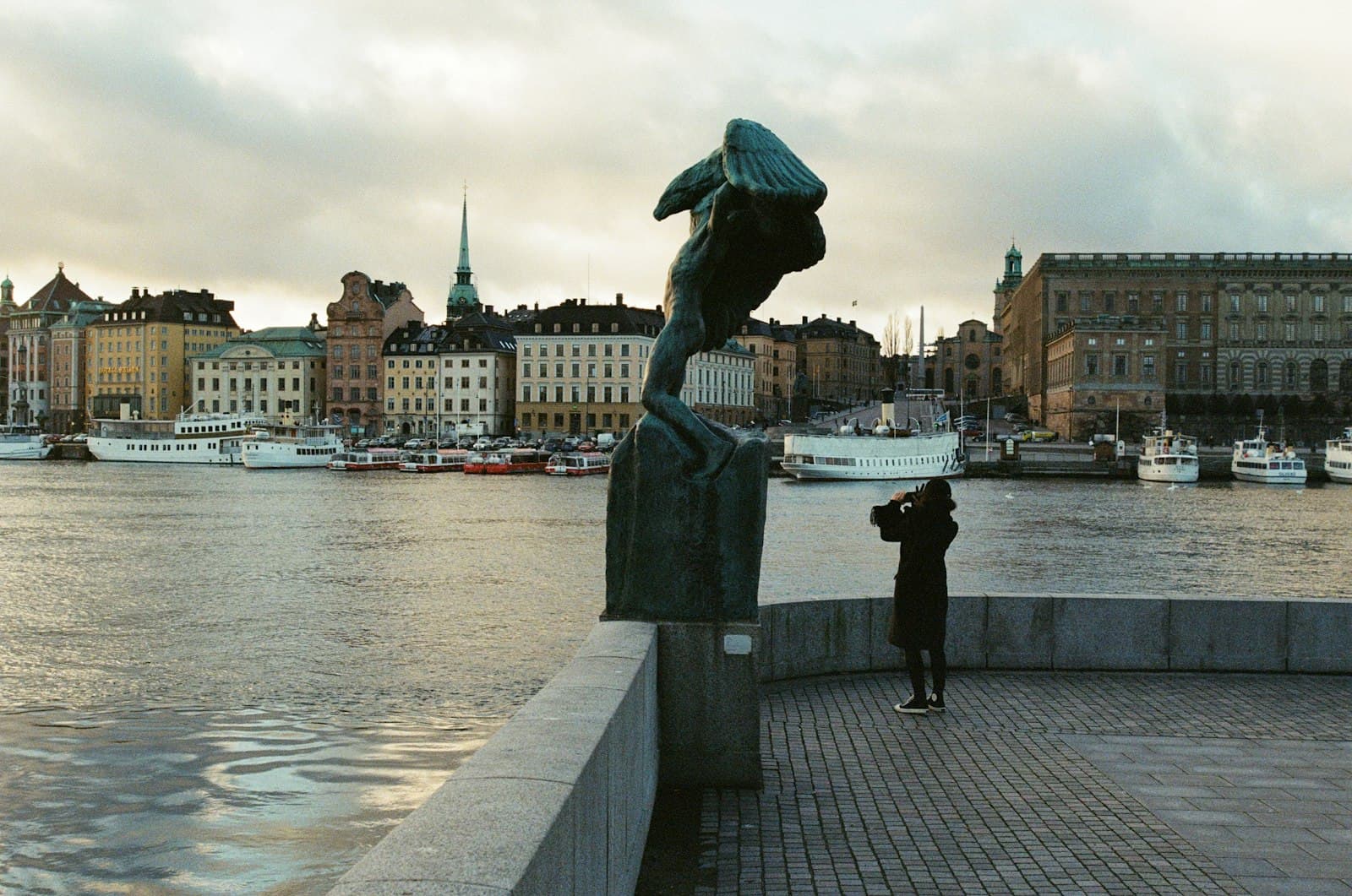 The Girl with the Dragon Tattoo — statue of man holding umbrella near body of water during daytime