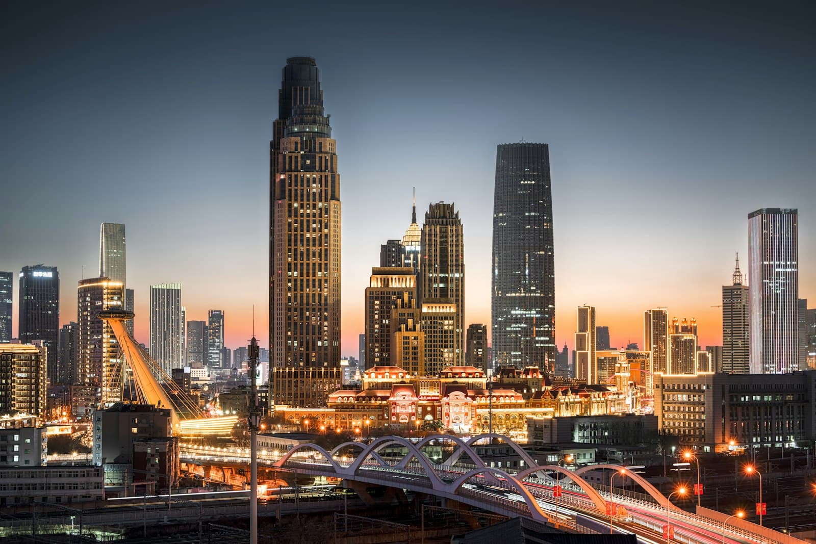Tianjin — a view of a city at night with a bridge in the foreground