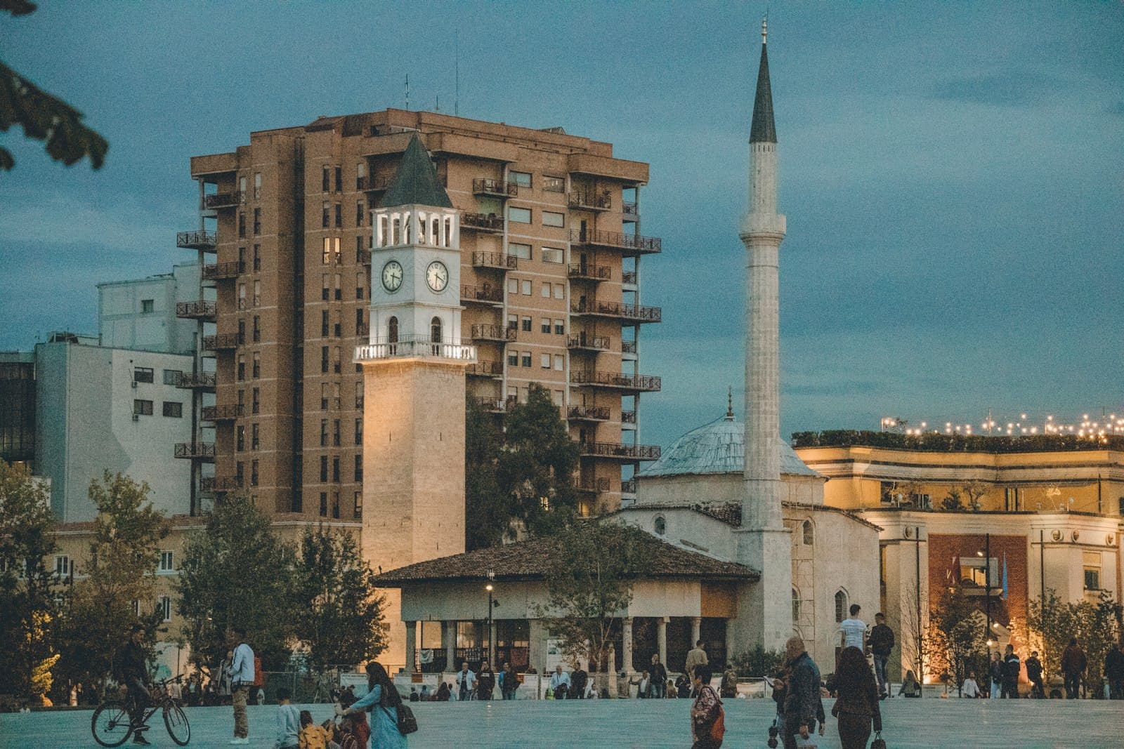 Tirana — a group of people walking around a plaza with a clock tower in the background