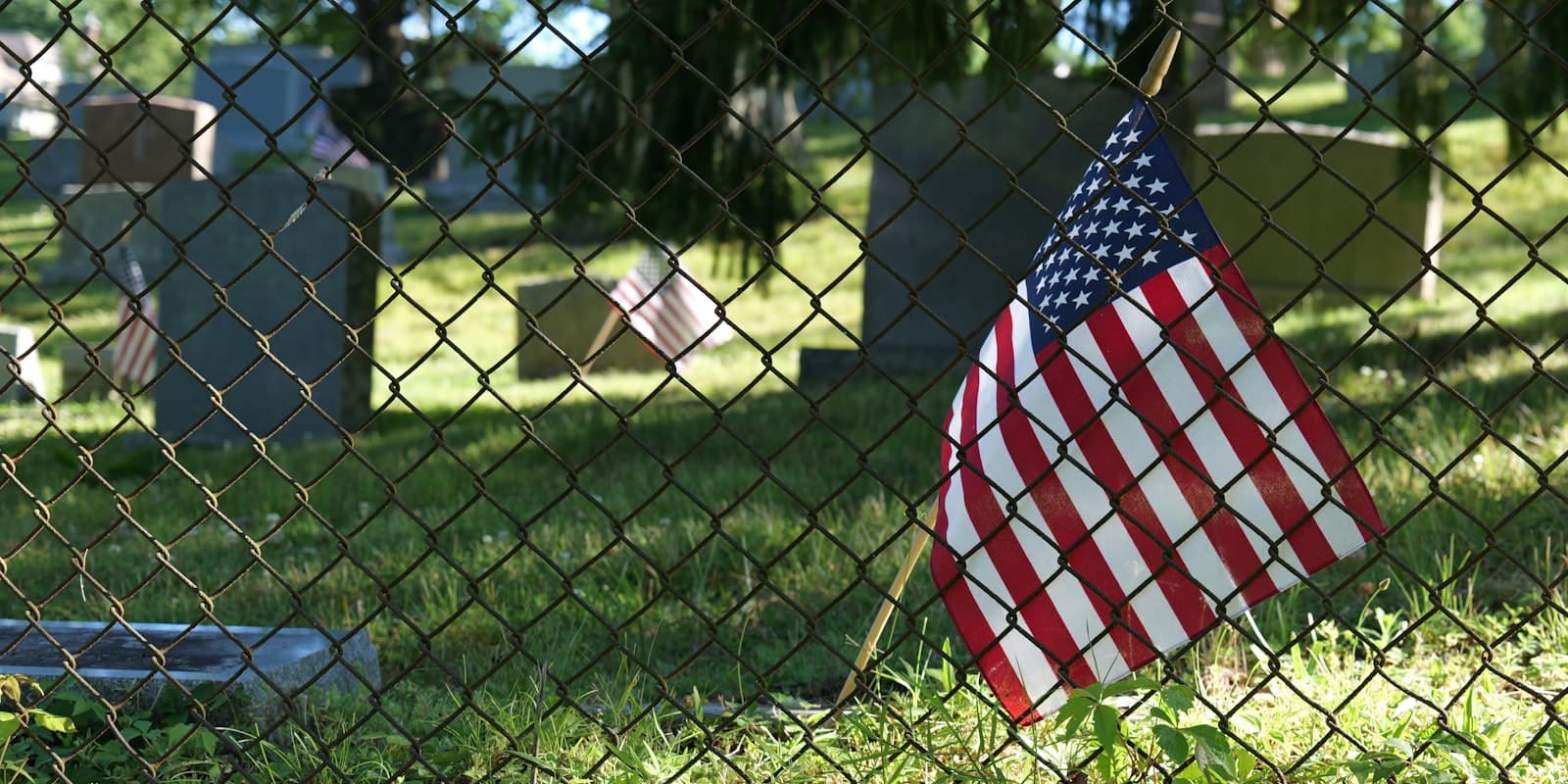 Tombstone — An american flag hanging on a chain link fence