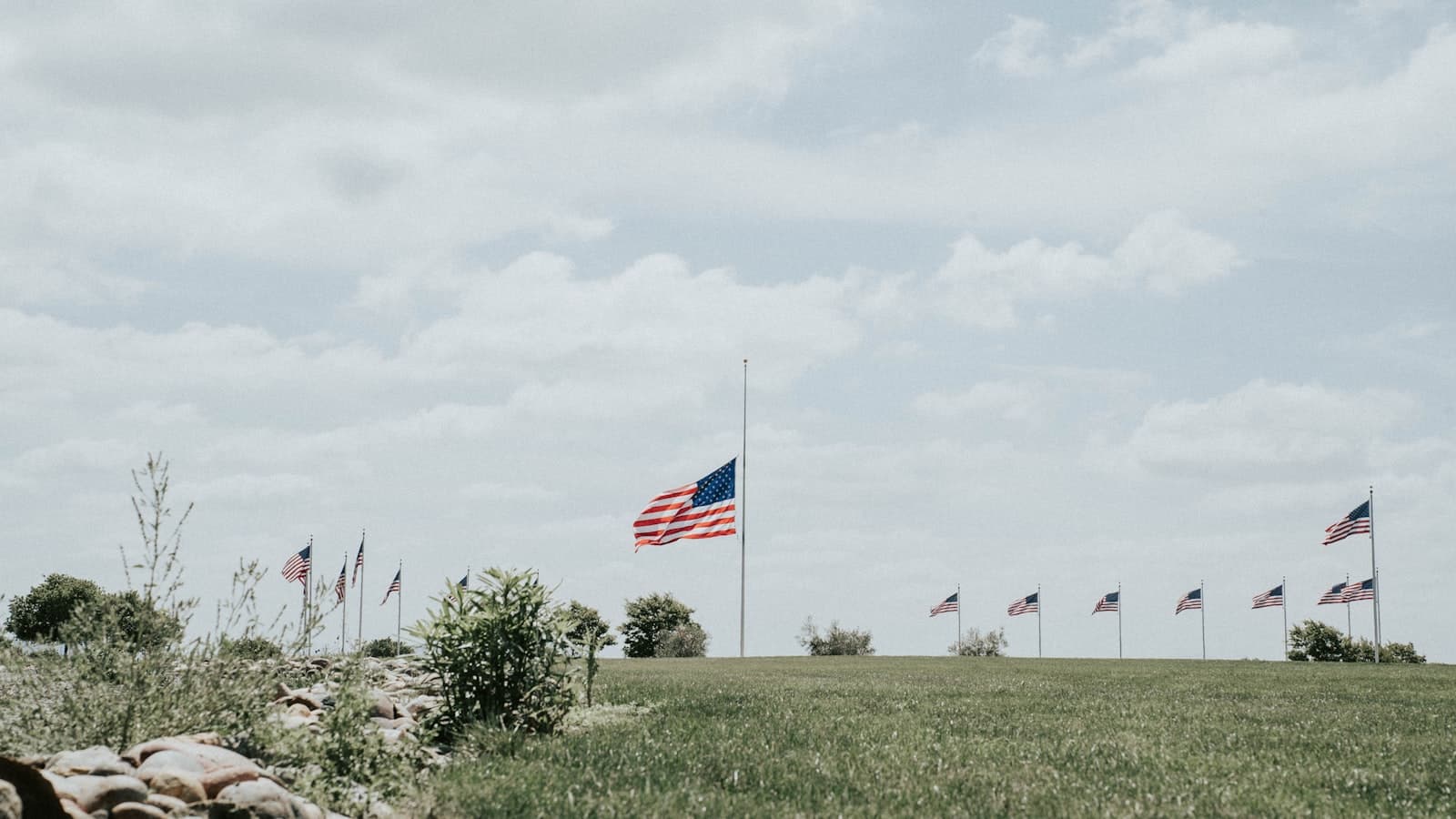 Tombstone — flags on green grass field under white cloudy sky during daytime