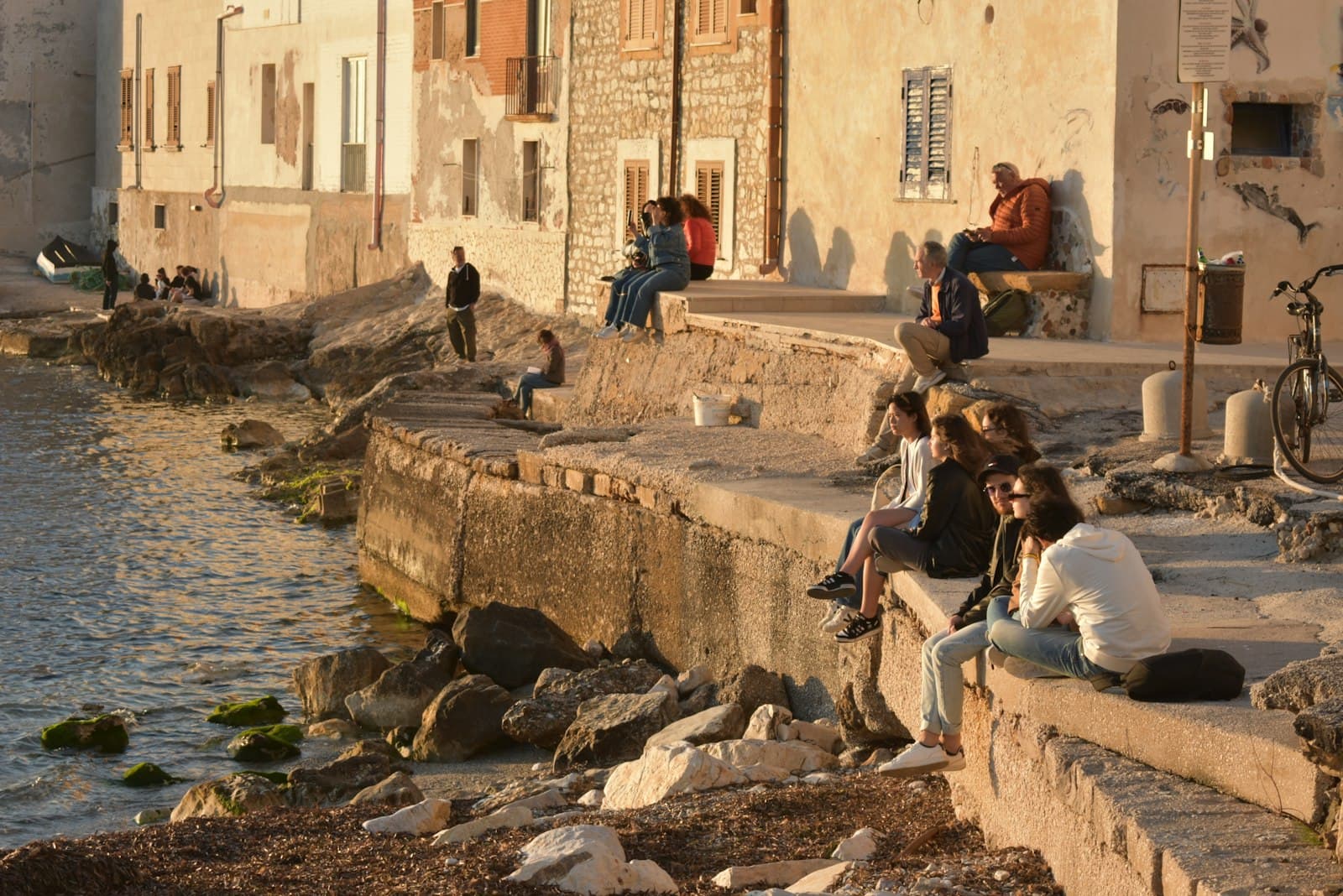 Trapani — a group of people sitting next to a body of water