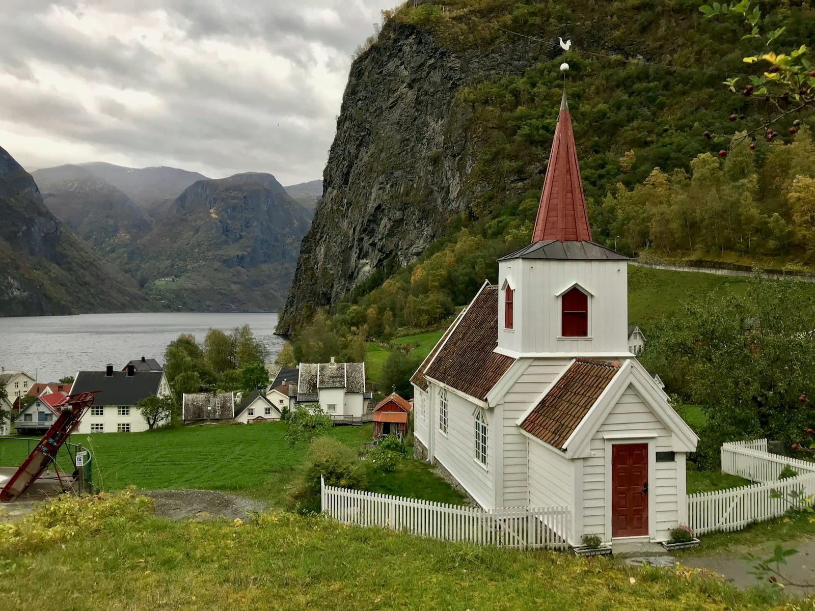 Undredal — white and red concrete house near green mountain during daytime