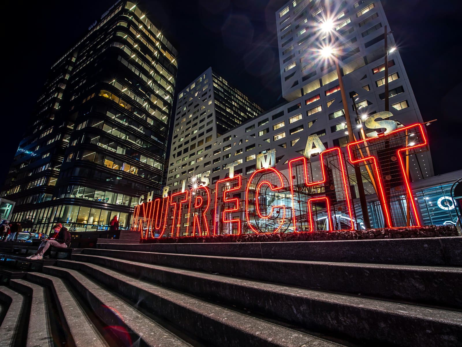 Utrecht — red and white train rail in between high rise buildings during nighttime