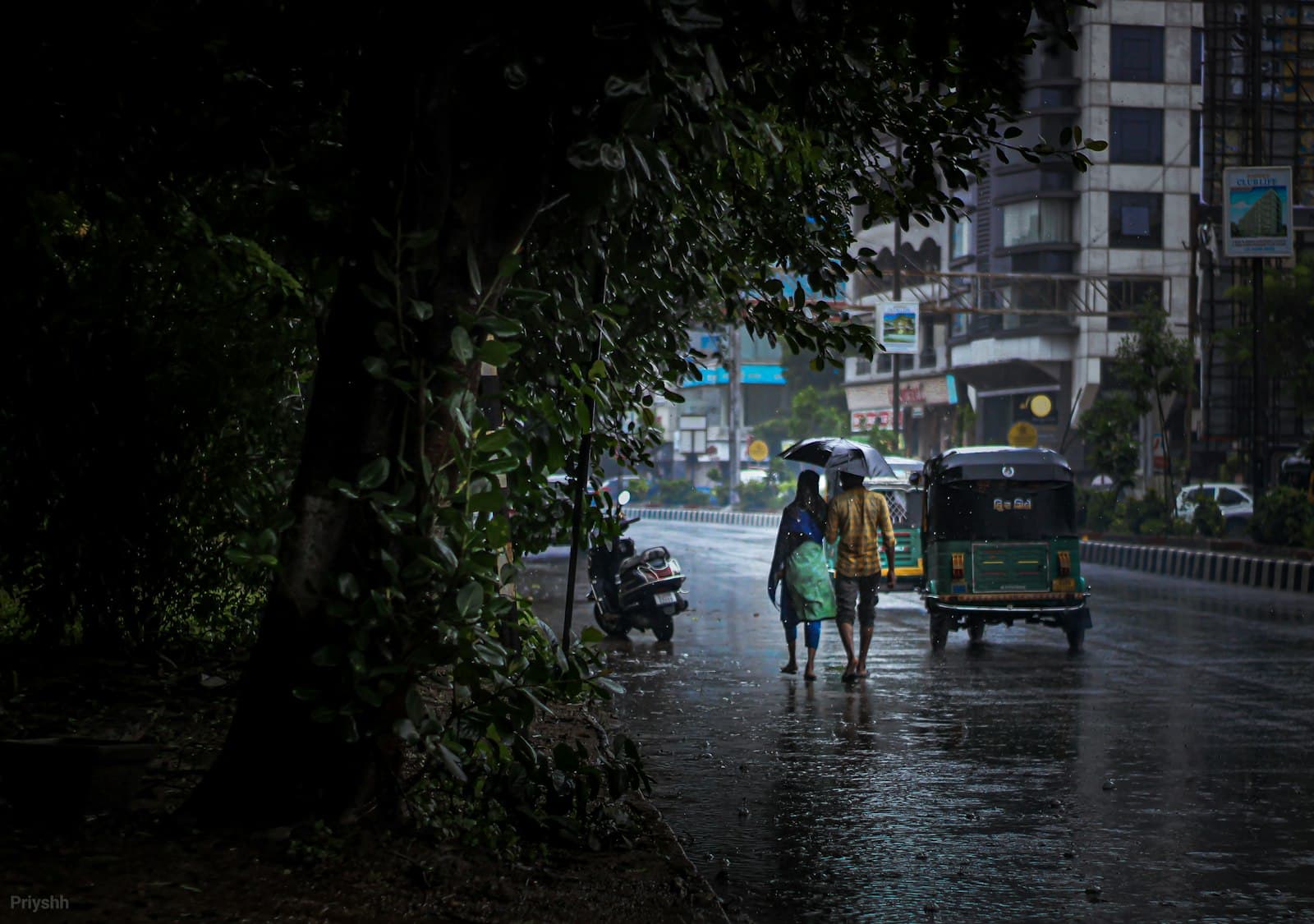 Vadodara — a couple of people walking down a rain soaked street