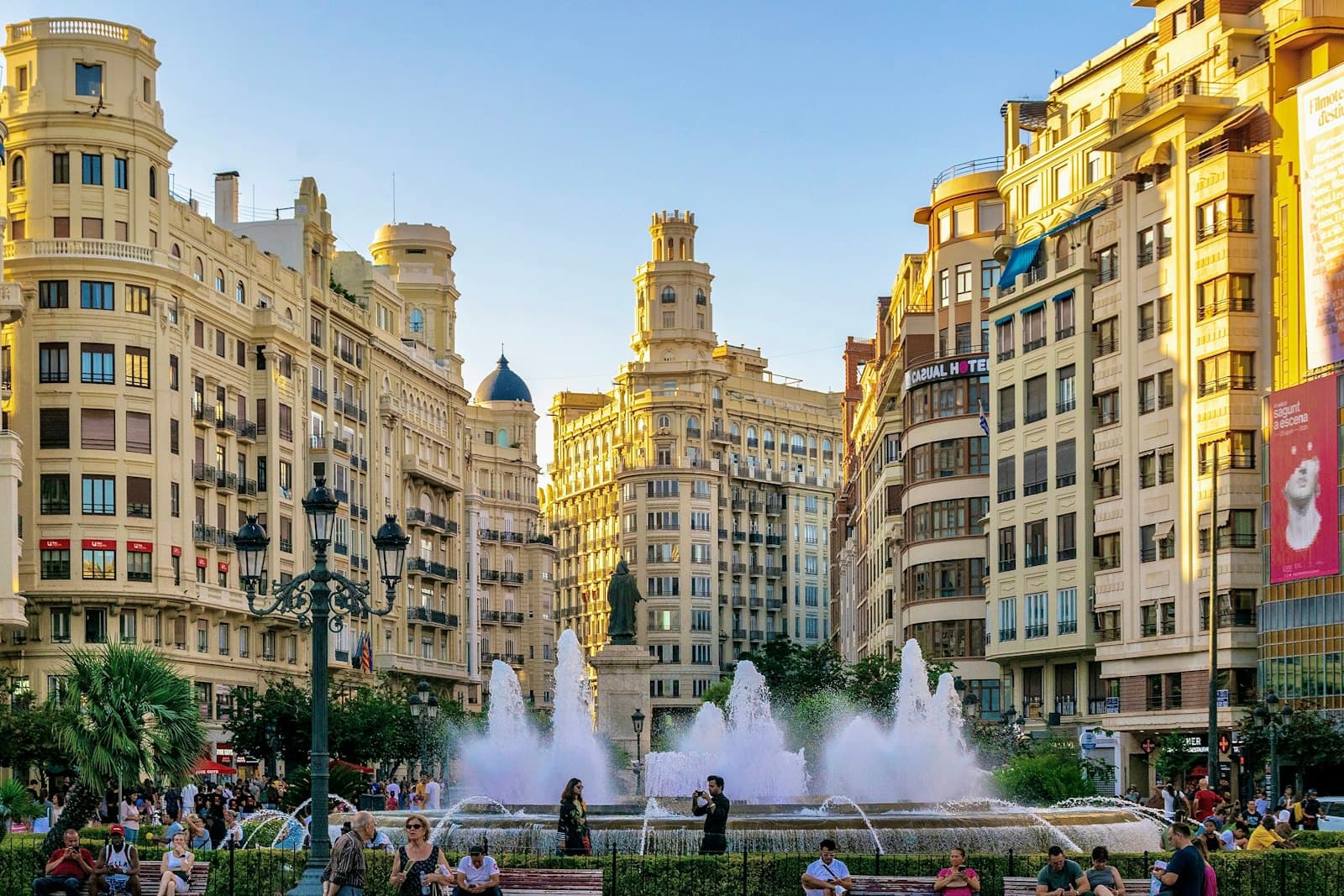 Valencia — A group of people standing around a fountain in a city