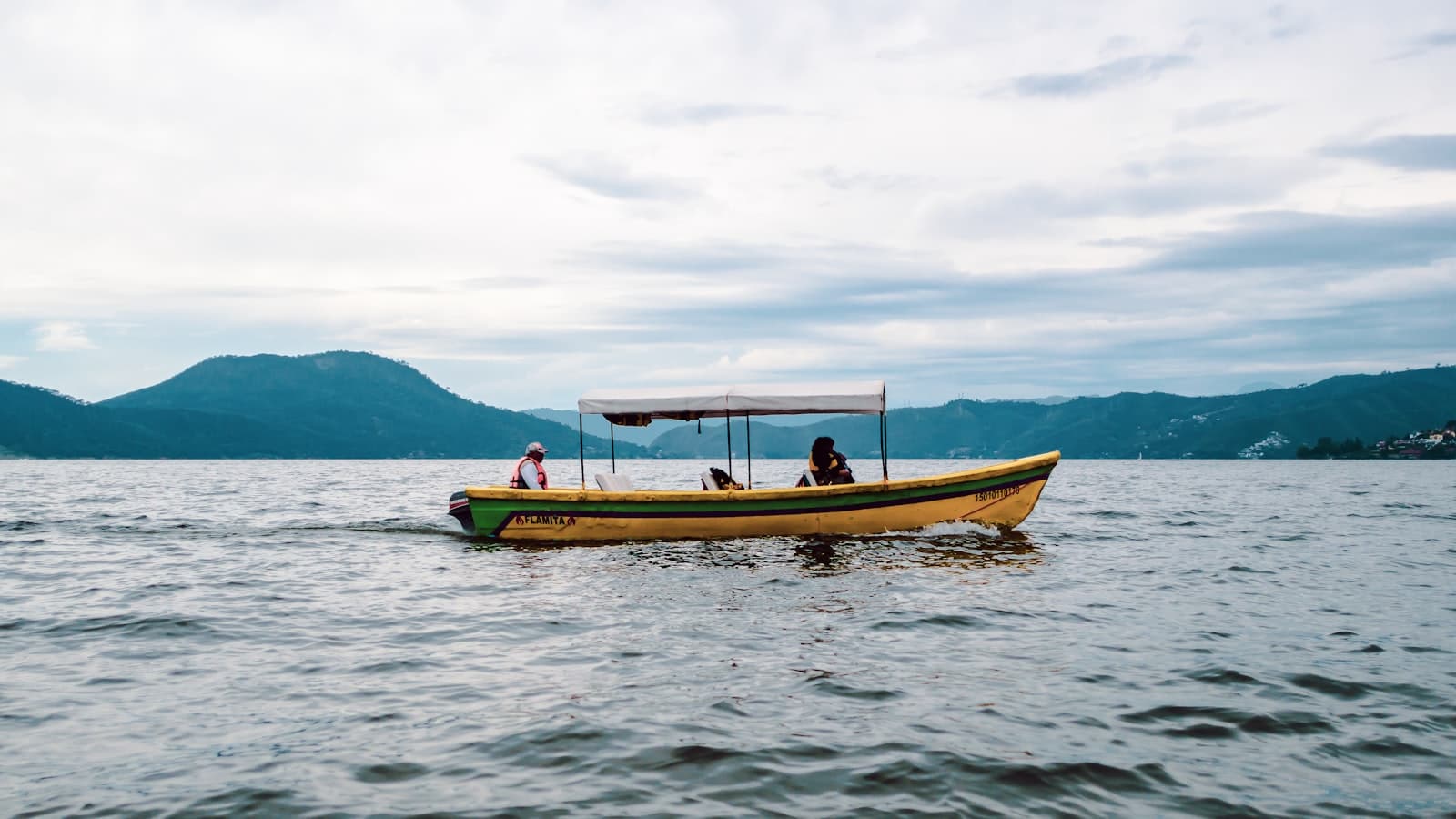 Valle de Bravo — a yellow boat with two people on it in the water