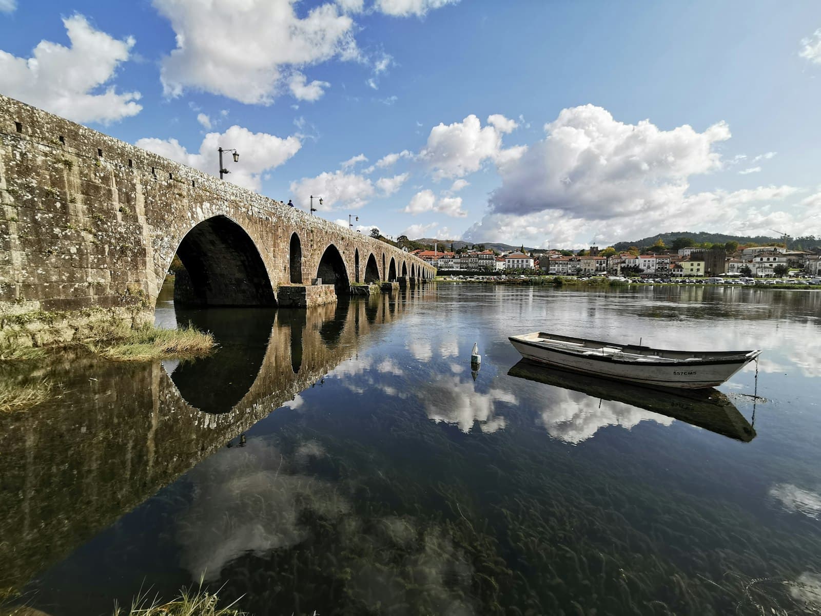 Viana do Castelo — white wooden row boat on clear water near bridge under blue sky and white clouds during day time