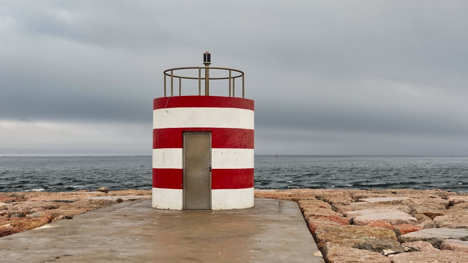 Vila Real de Santo António — a red and white striped structure on a rocky beach