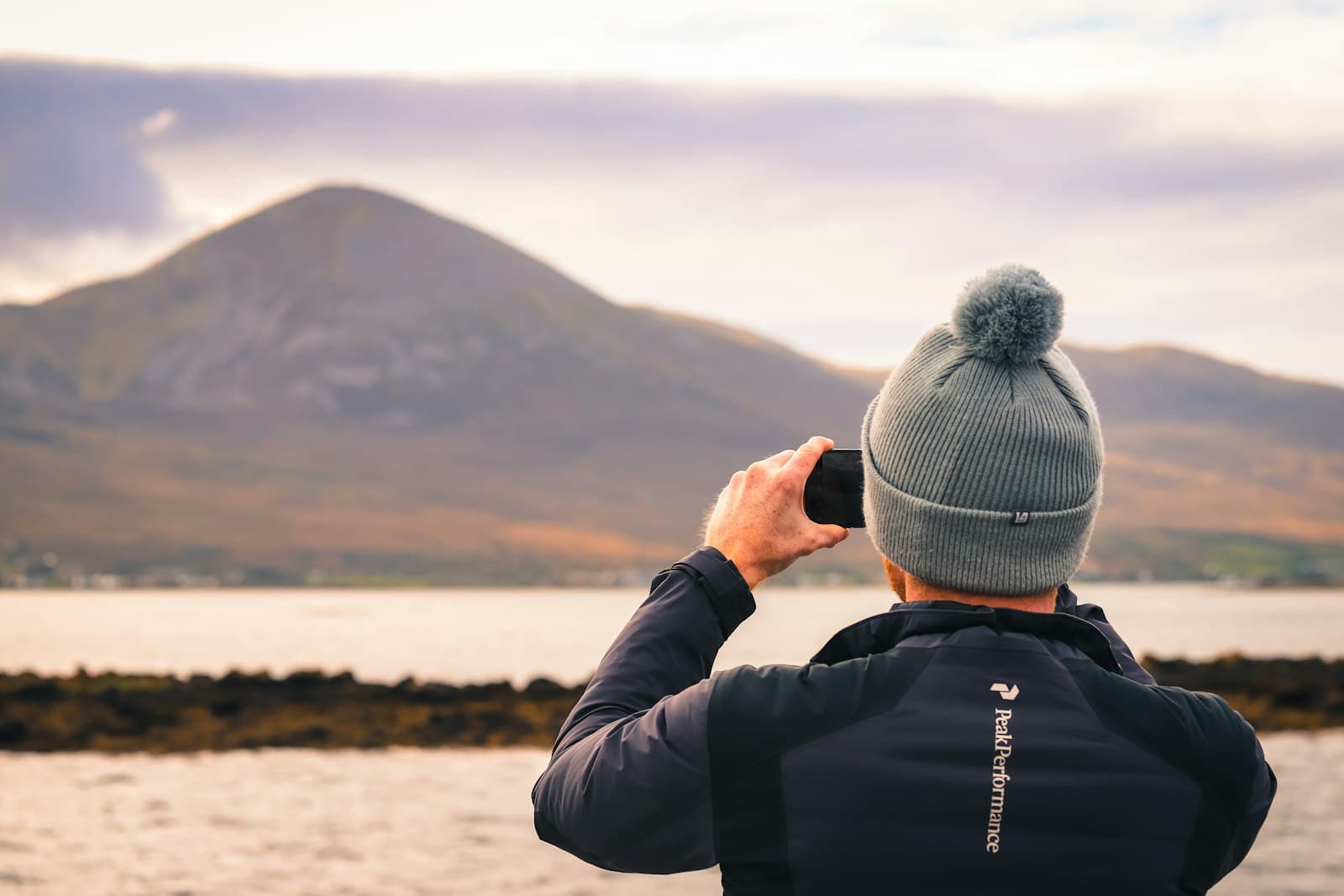 Westport — man in black jacket and gray knit cap taking photo of mountain during daytime