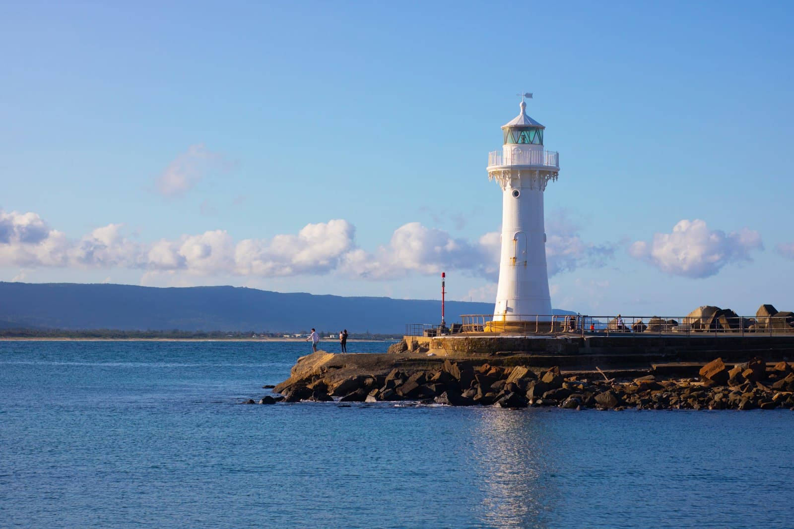 Wollongong — white lighthouse on brown rock formation near body of water during daytime