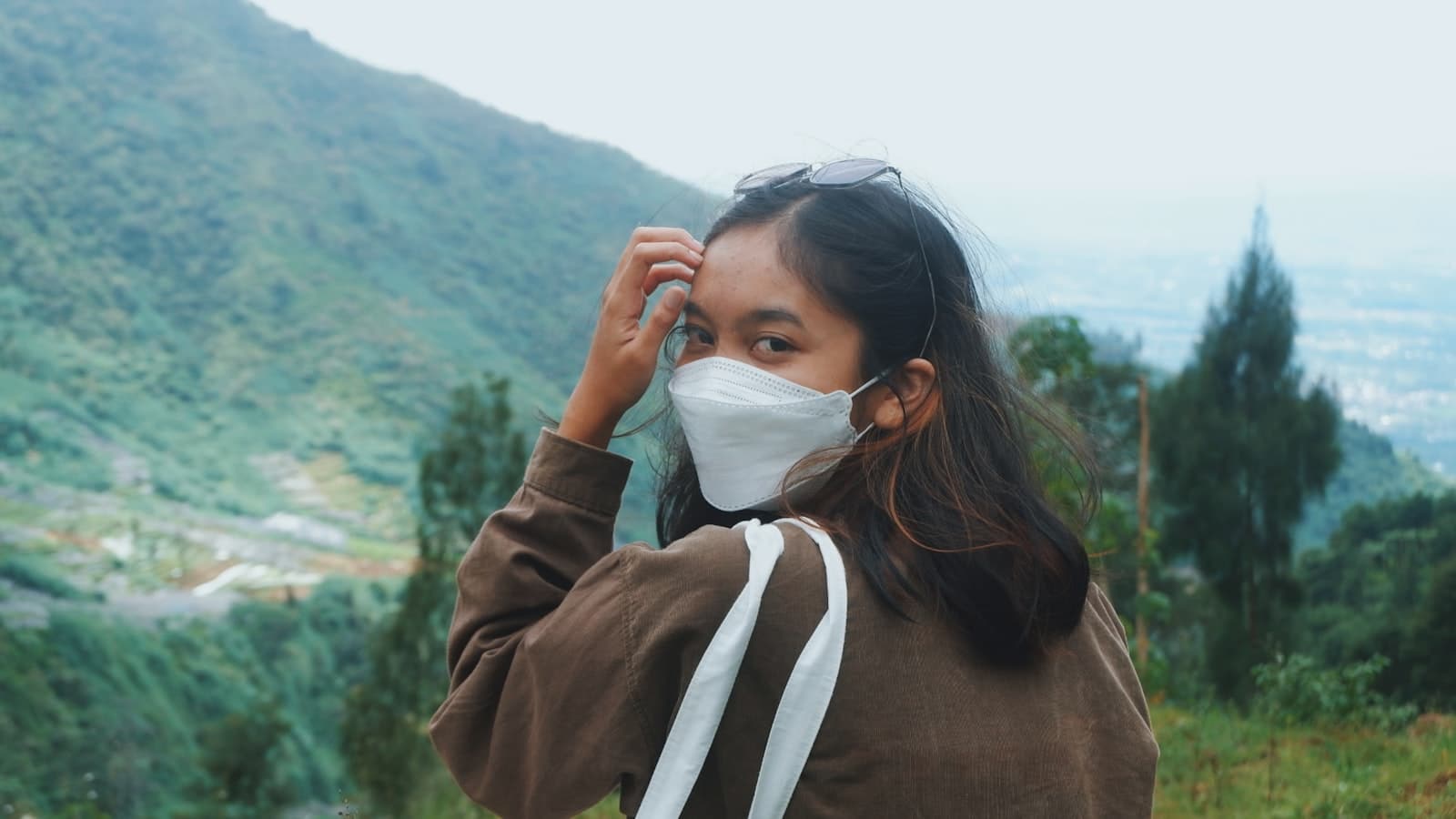 Wonosobo — a woman wearing a face mask while standing on top of a hill