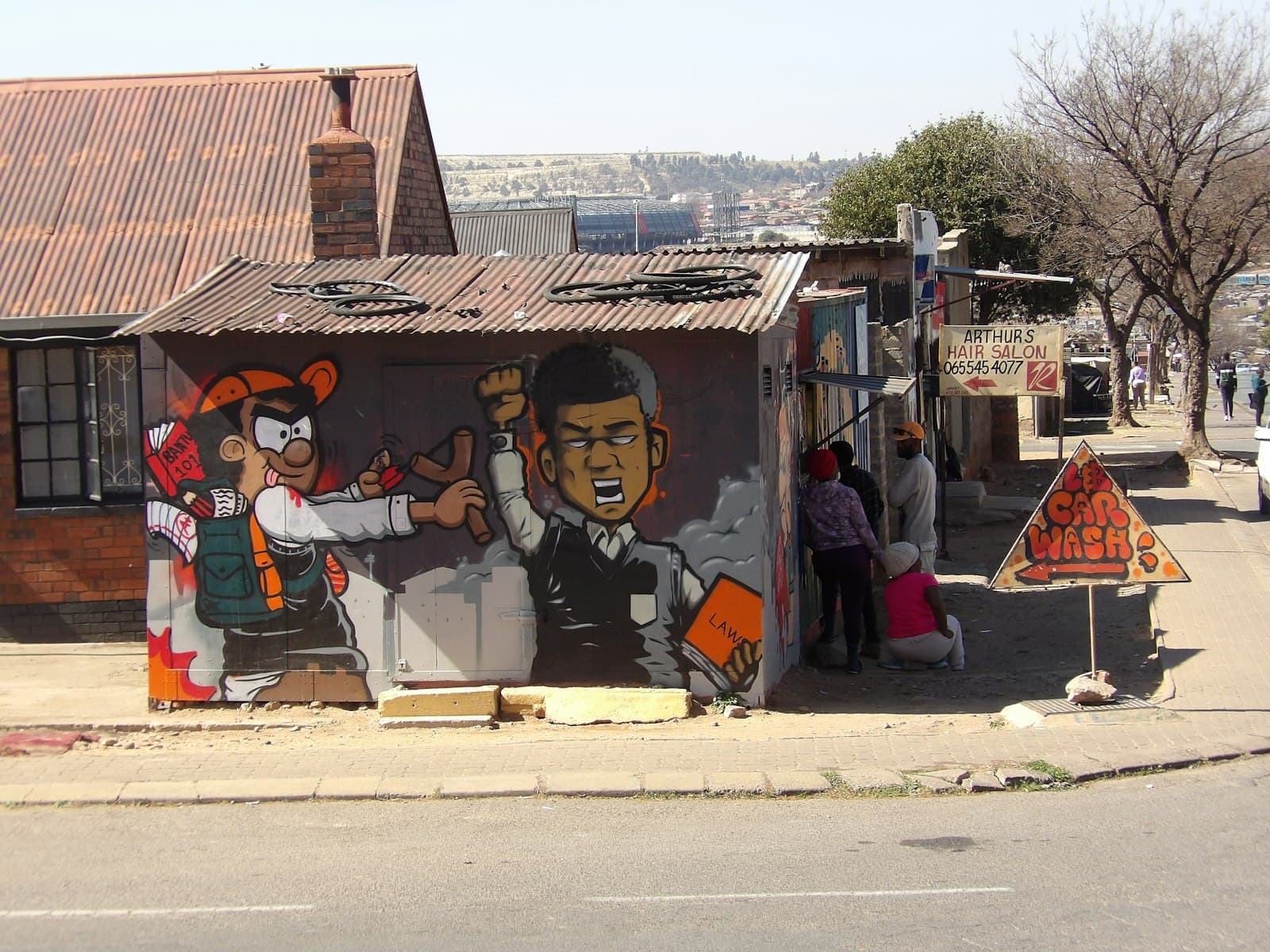 Woodstock Street Art — Graffiti art on a corrugated iron shack with people nearby.
