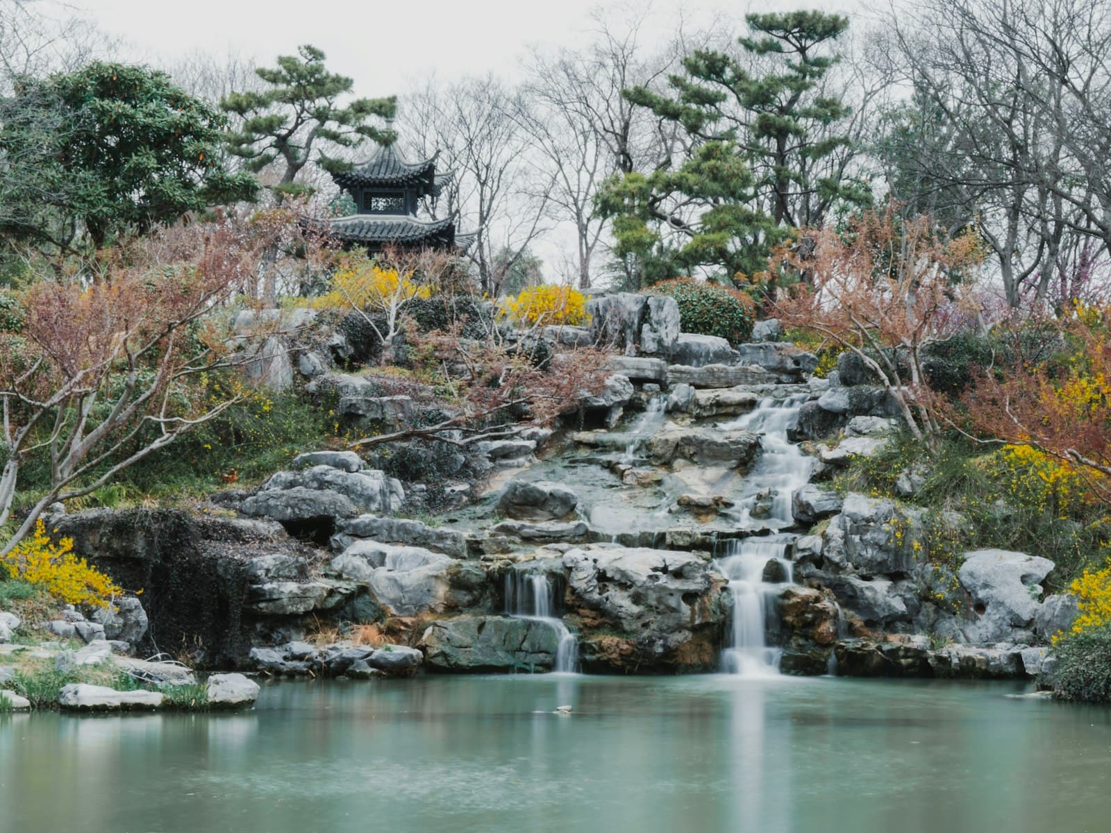 Yangzhou — A waterfall cascades into a pond in a beautiful garden.