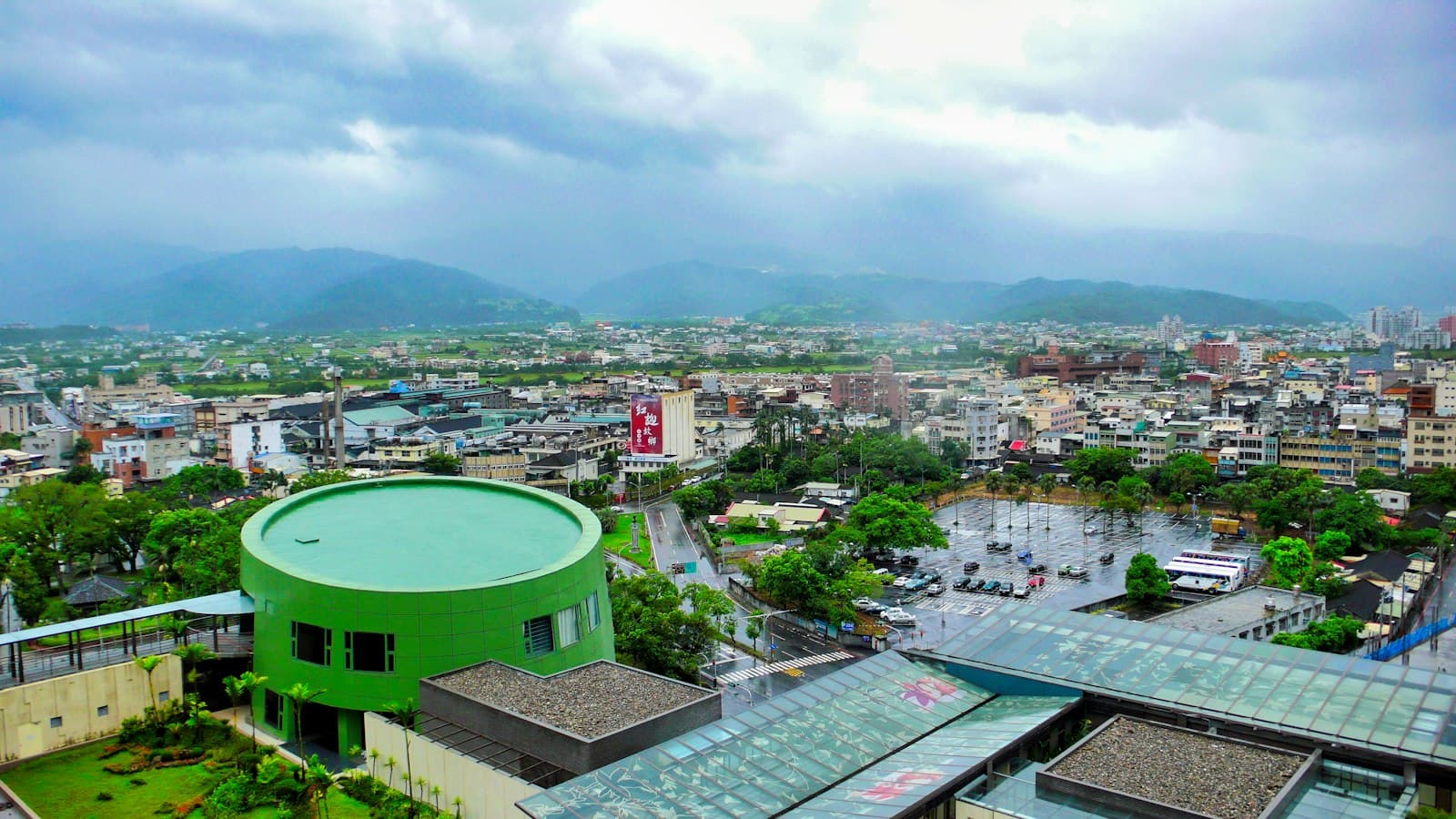 Yilan — a green building in a city with mountains in the background