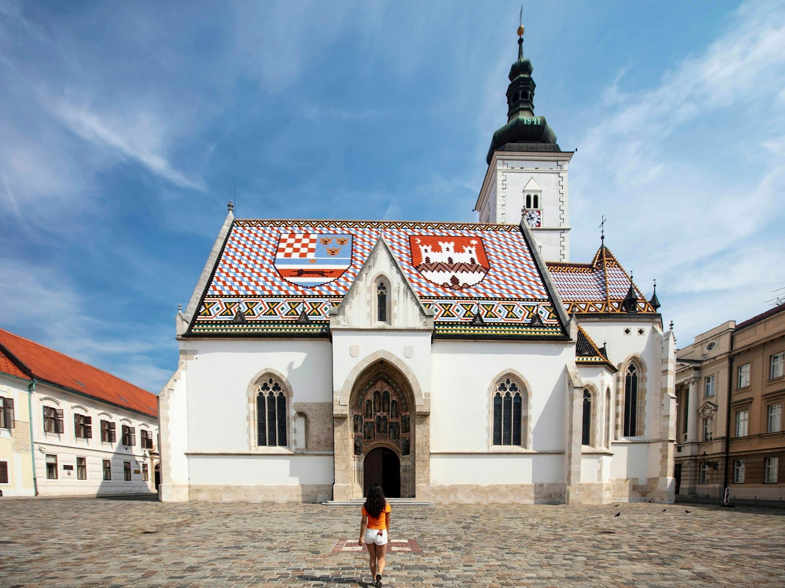 Zagreb — a person standing in front of a white building with a red roof